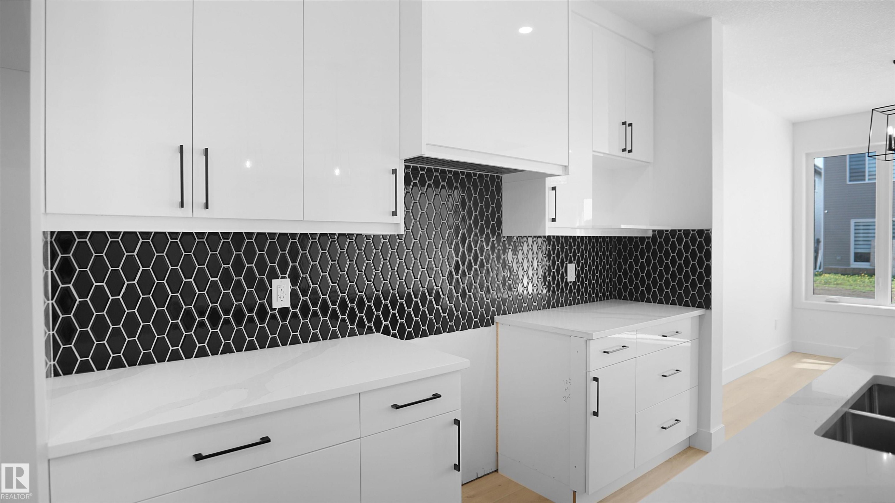 Kitchen featuring white cabinetry, light stone counters, tasteful backsplash, and modern cabinets - 711 31 Avenue, Edmonton, AB - Indoor Photo Showing Kitchen