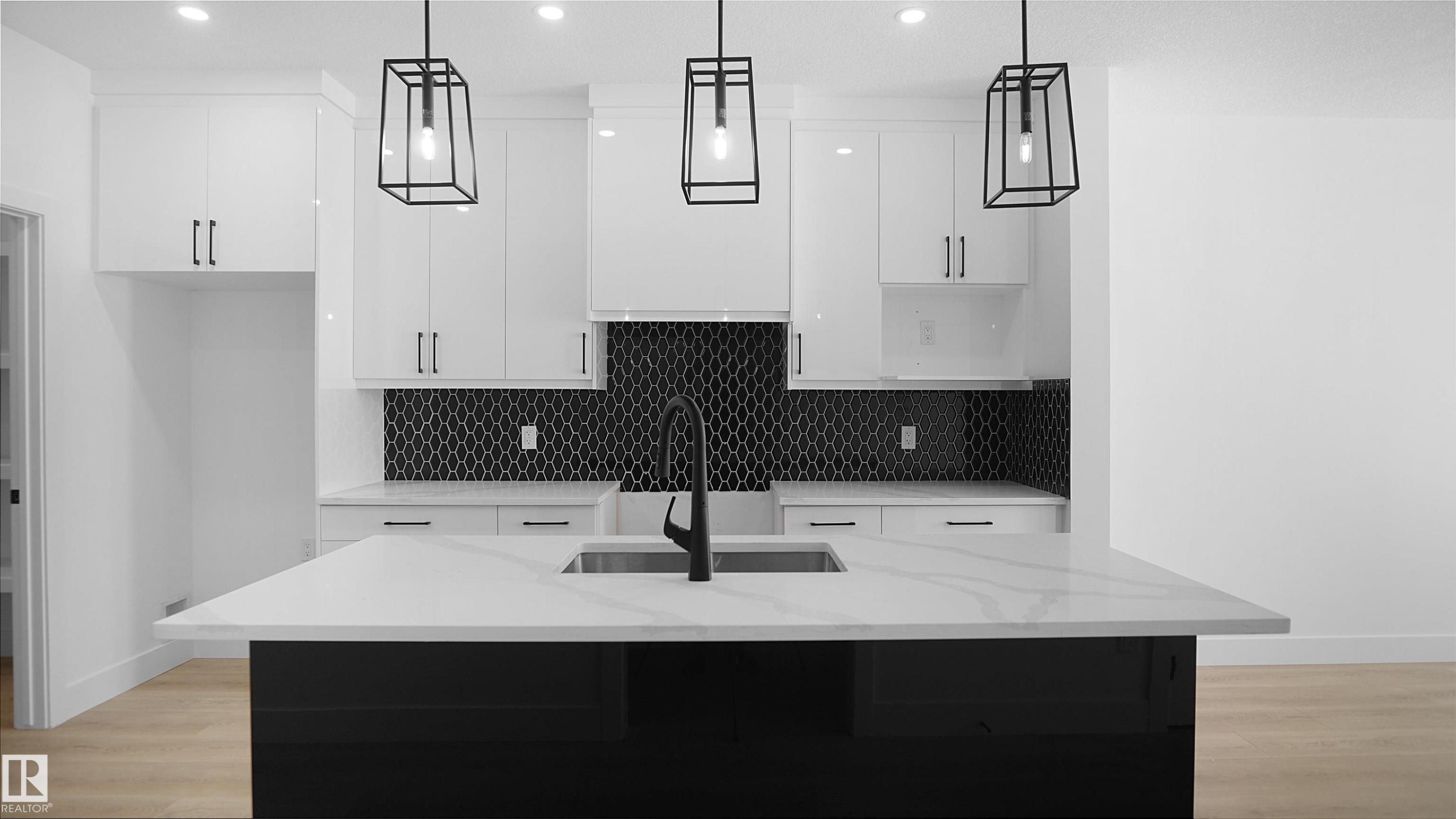 Dual tone kitchen featuring light stone counters, an island with sink, light wood-type flooring, and two tone cabinetry - 711 31 Avenue, Edmonton, AB - Indoor Photo Showing Kitchen With Upgraded Kitchen