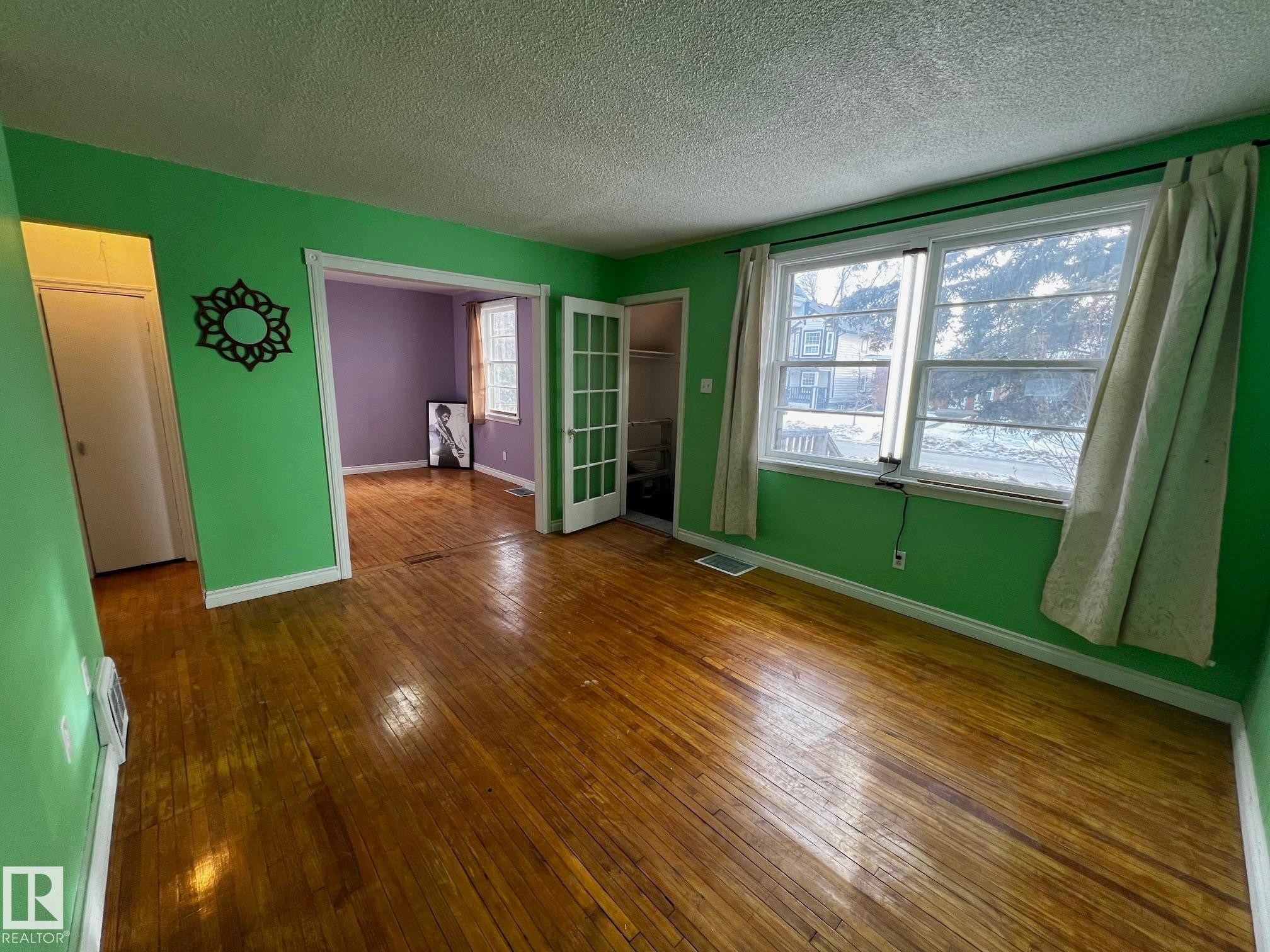 Empty room with dark wood-type flooring and a textured ceiling - 10830 68 Avenue, Edmonton, AB - Indoor