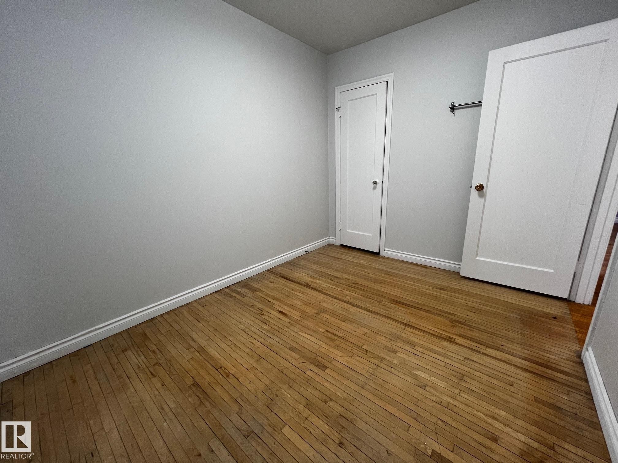 Unfurnished bedroom featuring hardwood / wood-style floors and baseboards - 10830 68 Avenue, Edmonton, AB - Indoor Photo Showing Other Room