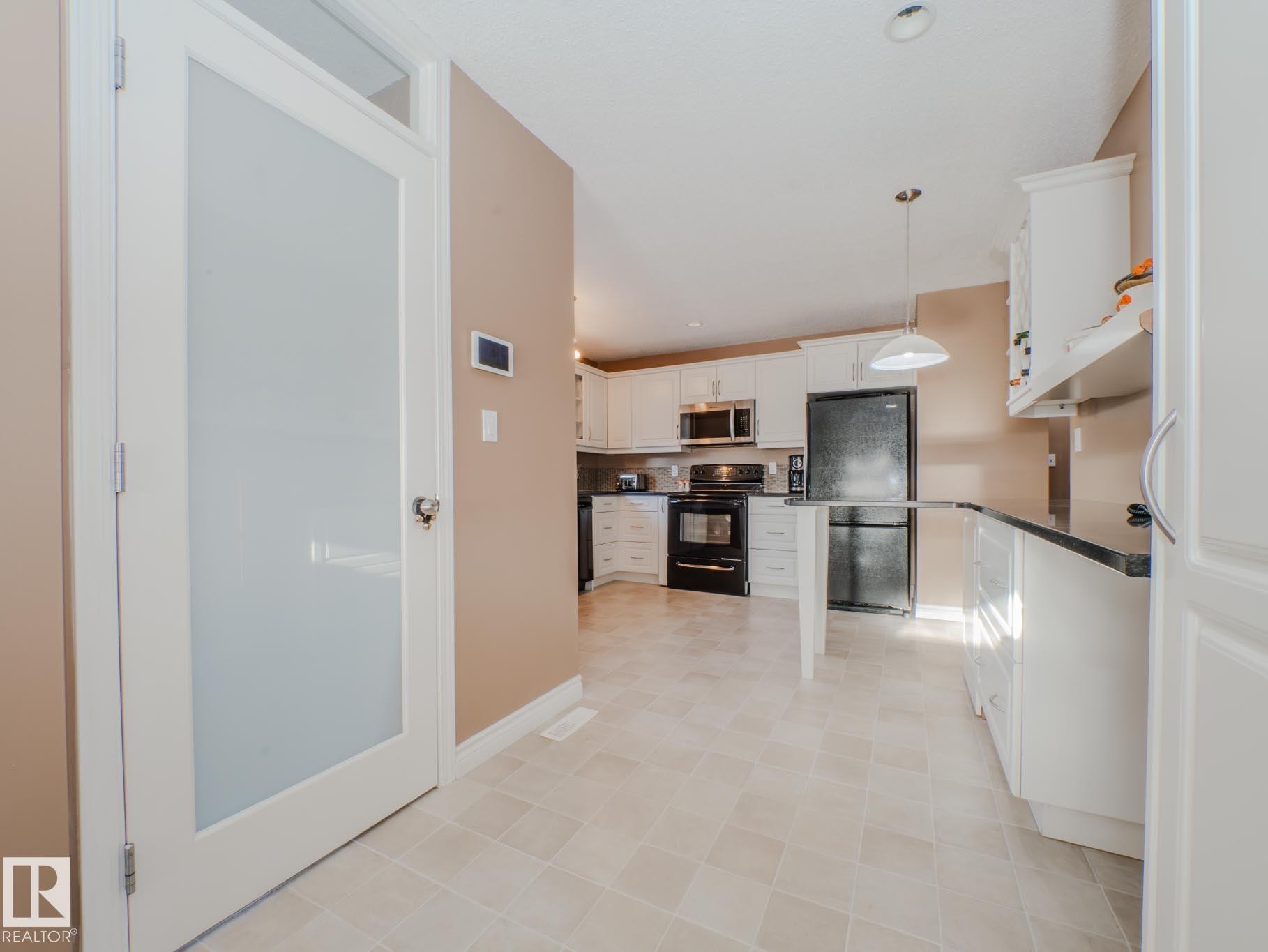Kitchen with white cabinetry, hanging light fixtures, black appliances, recessed lighting, and dark stone counters - 3204 113B Street, Edmonton, AB - Indoor Photo Showing Kitchen
