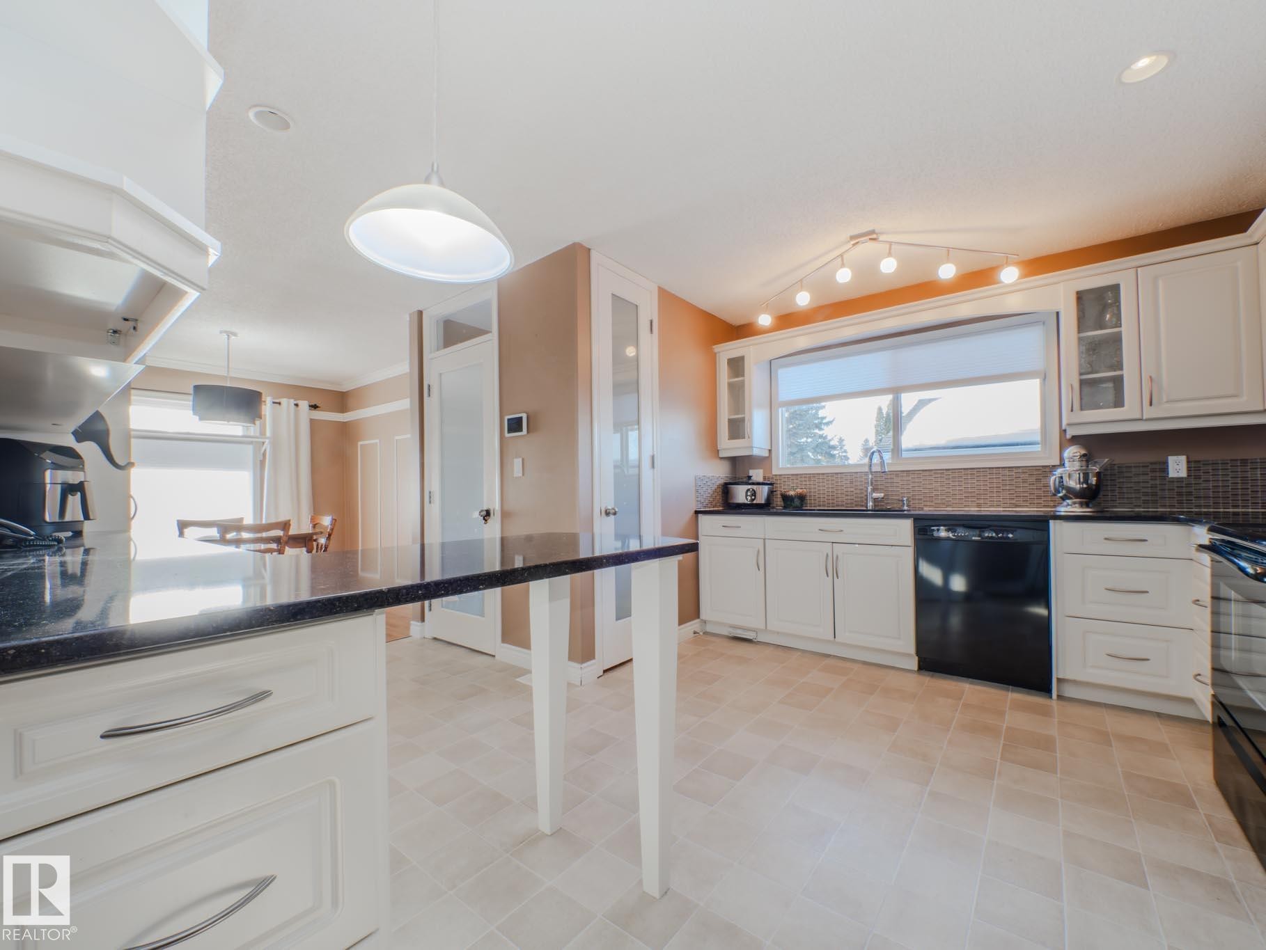 Kitchen with hanging light fixtures, glass insert cabinets, white cabinetry, and black appliances - 3204 113B Street, Edmonton, AB - Indoor Photo Showing Kitchen With Upgraded Kitchen