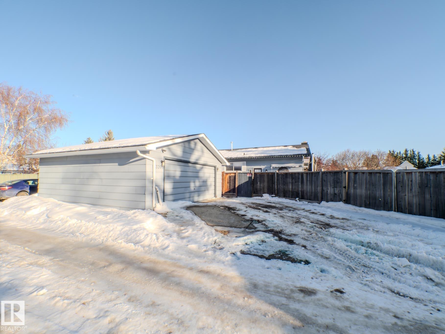 View of snowy exterior featuring a detached garage and an outbuilding - 3204 113B Street, Edmonton, AB - Outdoor
