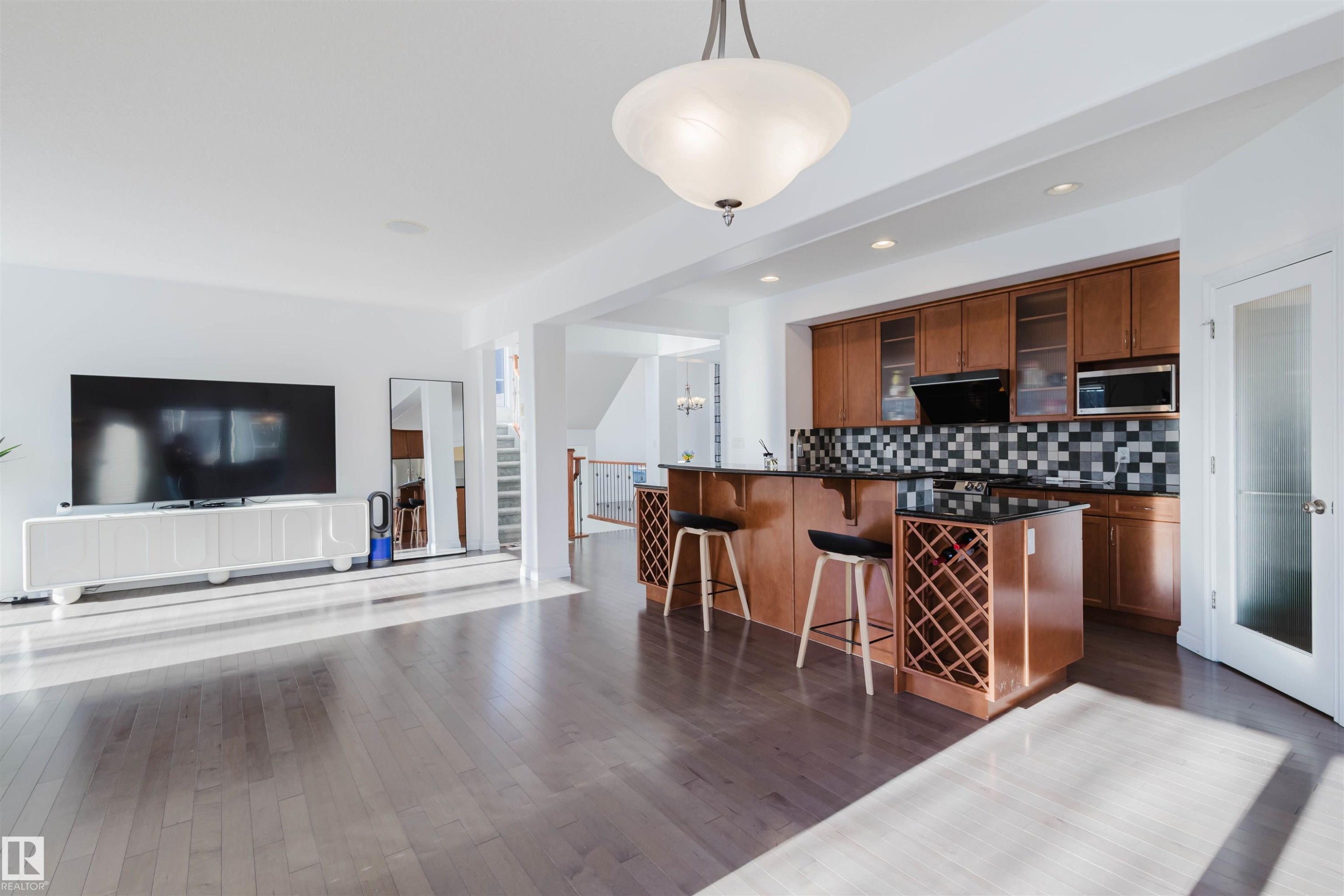 Kitchen featuring open floor plan, a breakfast bar area, glass insert cabinets, wood finish cabinets, and dark wood-style flooring - 3547 Mclay Crescent, Edmonton, AB - Indoor