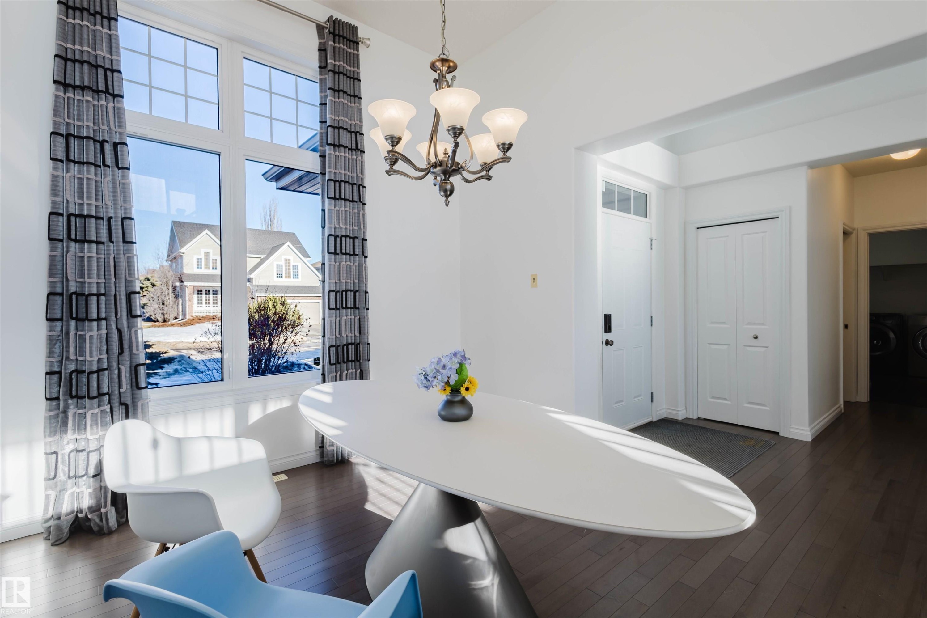 Dining area featuring a high ceiling, dark wood-type flooring, hanging lights, and washer and clothes dryer - 3547 Mclay Crescent, Edmonton, AB - Indoor
