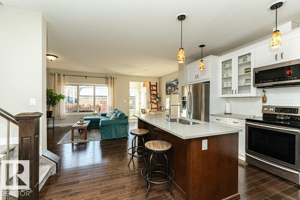 Two tone kitchen with stainless steel appliances, a breakfast bar, backsplash, open floor plan, and glass insert cabinets - 10535 67 Avenue, Edmonton, AB - Indoor Photo Showing Kitchen With Stainless Steel Kitchen With Upgraded Kitchen