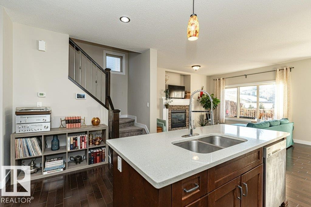 Kitchen with open floor plan, pendant lighting, dark wood-style floors, dark wood finish cabinetry, and a textured ceiling - 10535 67 Avenue, Edmonton, AB - Indoor Photo Showing Kitchen With Double Sink