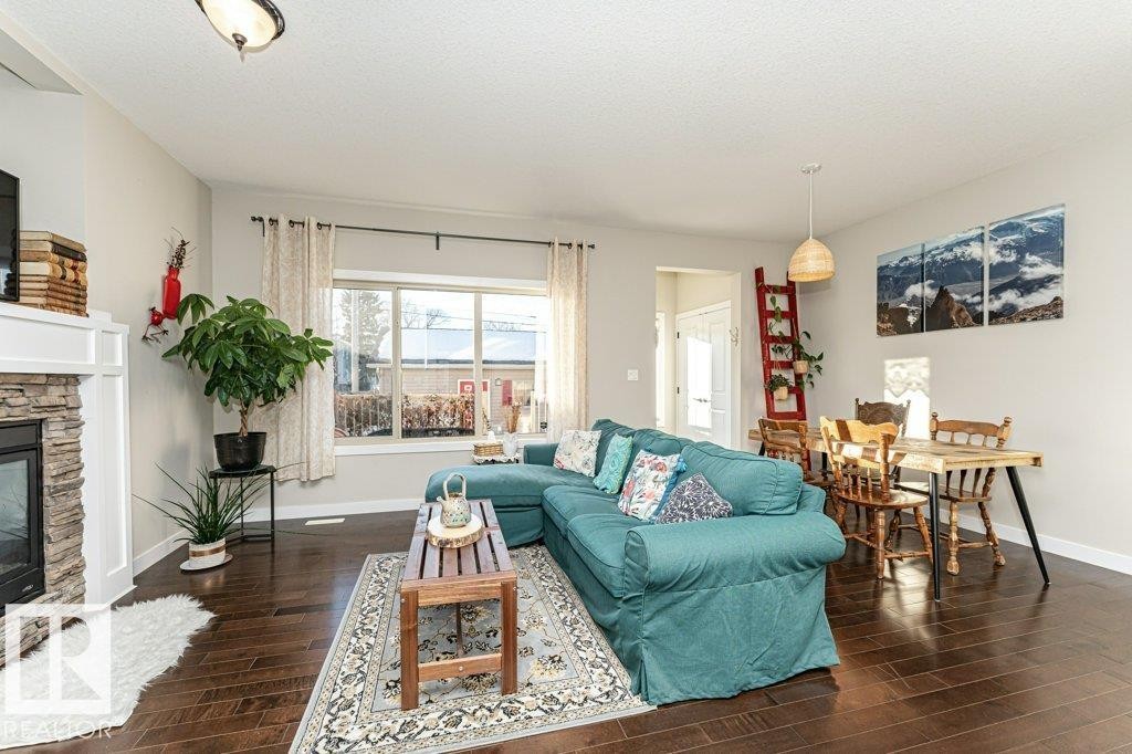Living area with dark wood-style floors, a stone fireplace, and a textured ceiling - 10535 67 Avenue, Edmonton, AB - Indoor Photo Showing Living Room With Fireplace