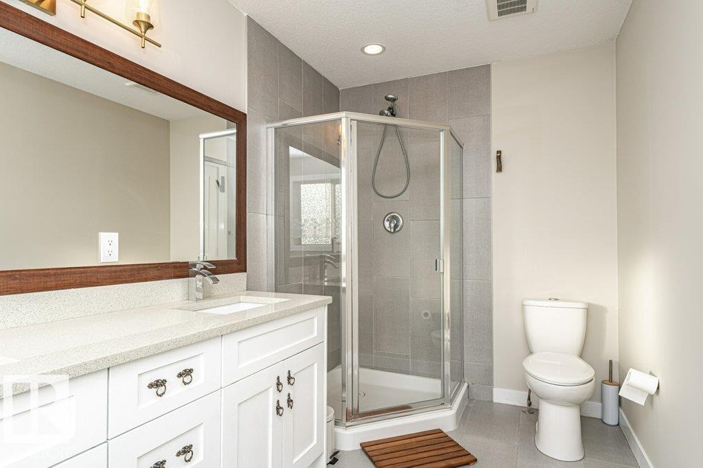 Bathroom with double vanity, a shower stall, light tile patterned floors, and a textured ceiling - 10535 67 Avenue, Edmonton, AB - Indoor Photo Showing Bathroom