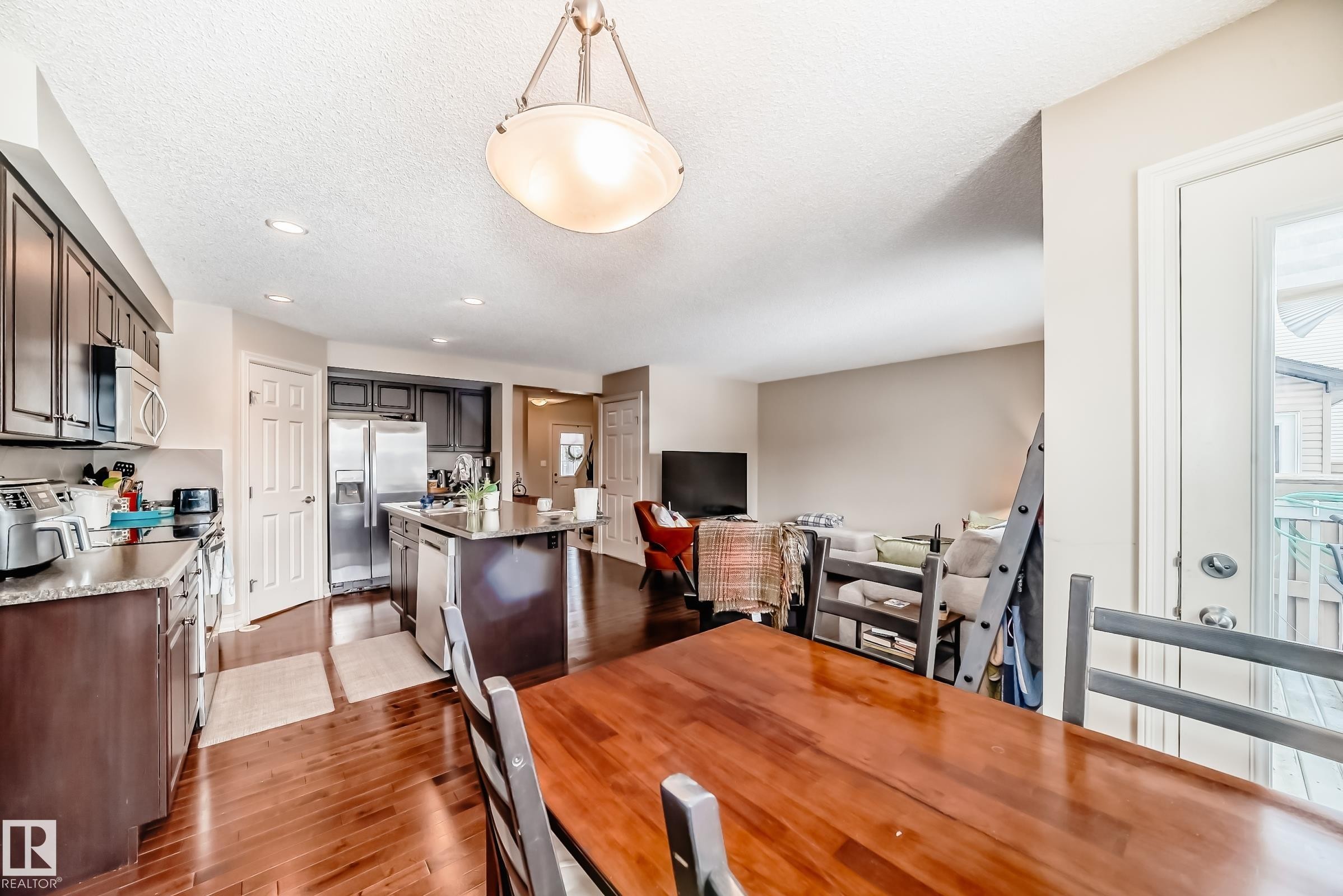 Dining room featuring dark wood-style floors, a textured ceiling, and recessed lighting - 9645 Simpson Place, Edmonton, AB