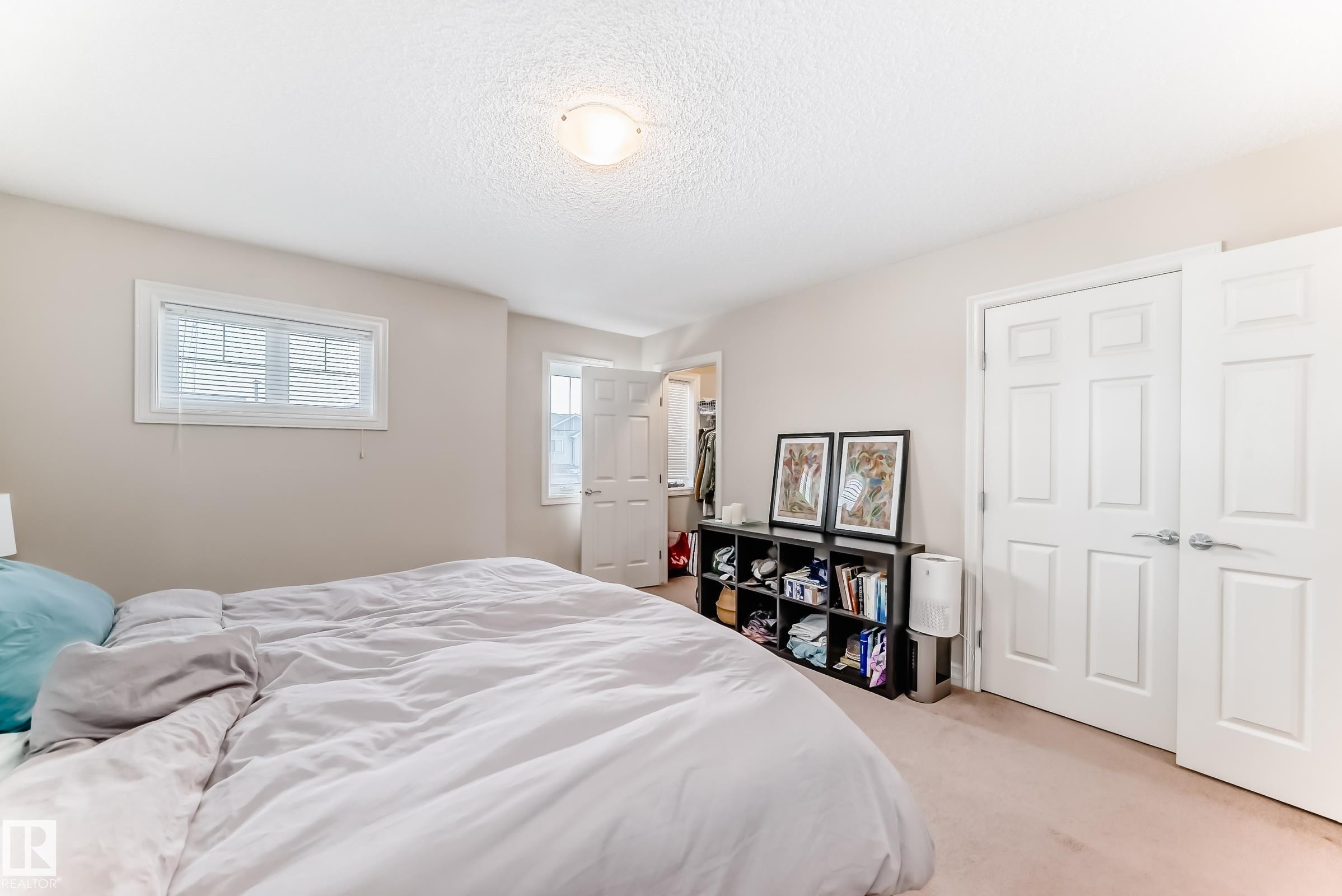 Bedroom with a spacious closet, carpet floors, and a textured ceiling - 9645 Simpson Place, Edmonton, AB