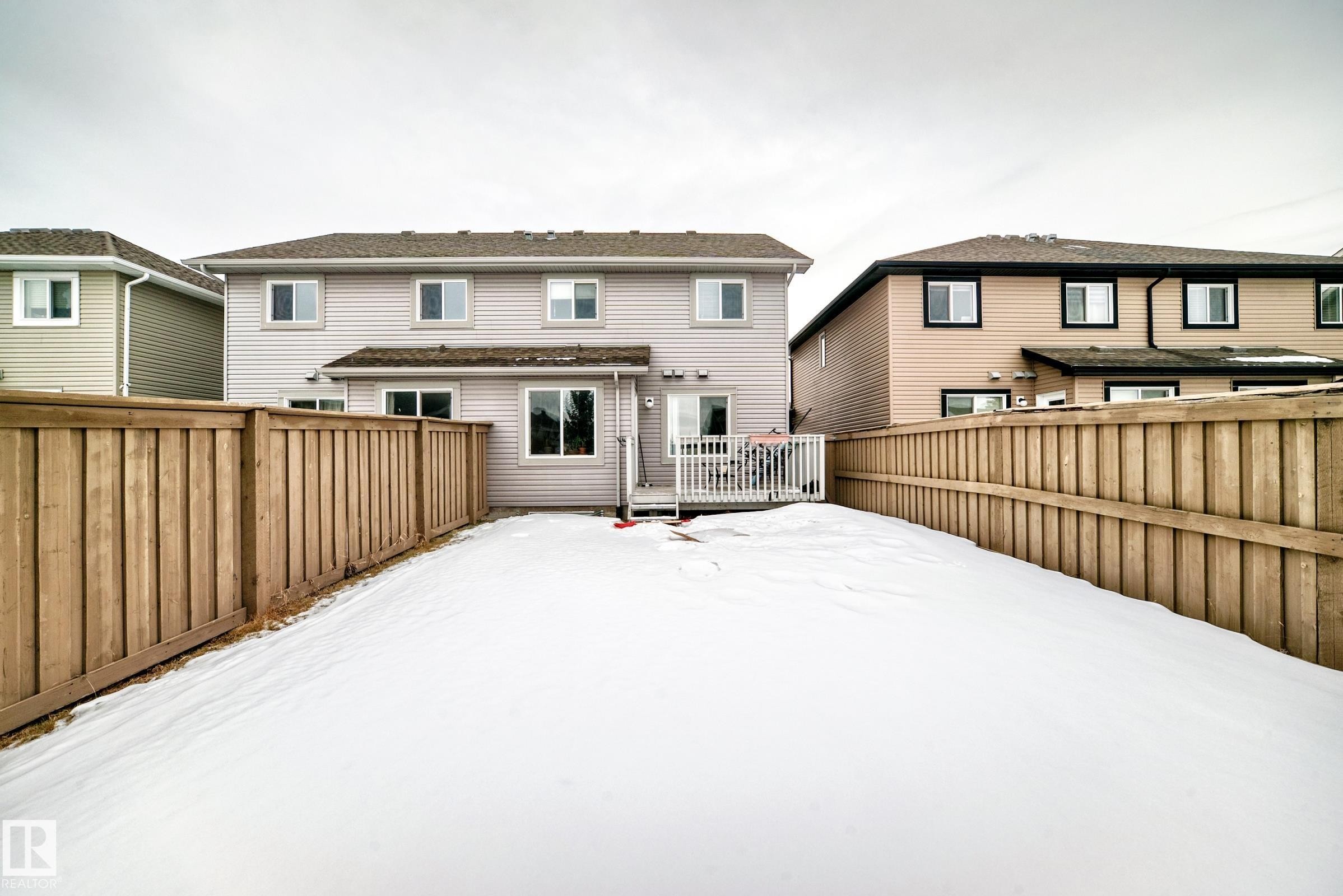 Snow covered house with a fenced backyard and a wooden deck - 9645 Simpson Place, Edmonton, AB