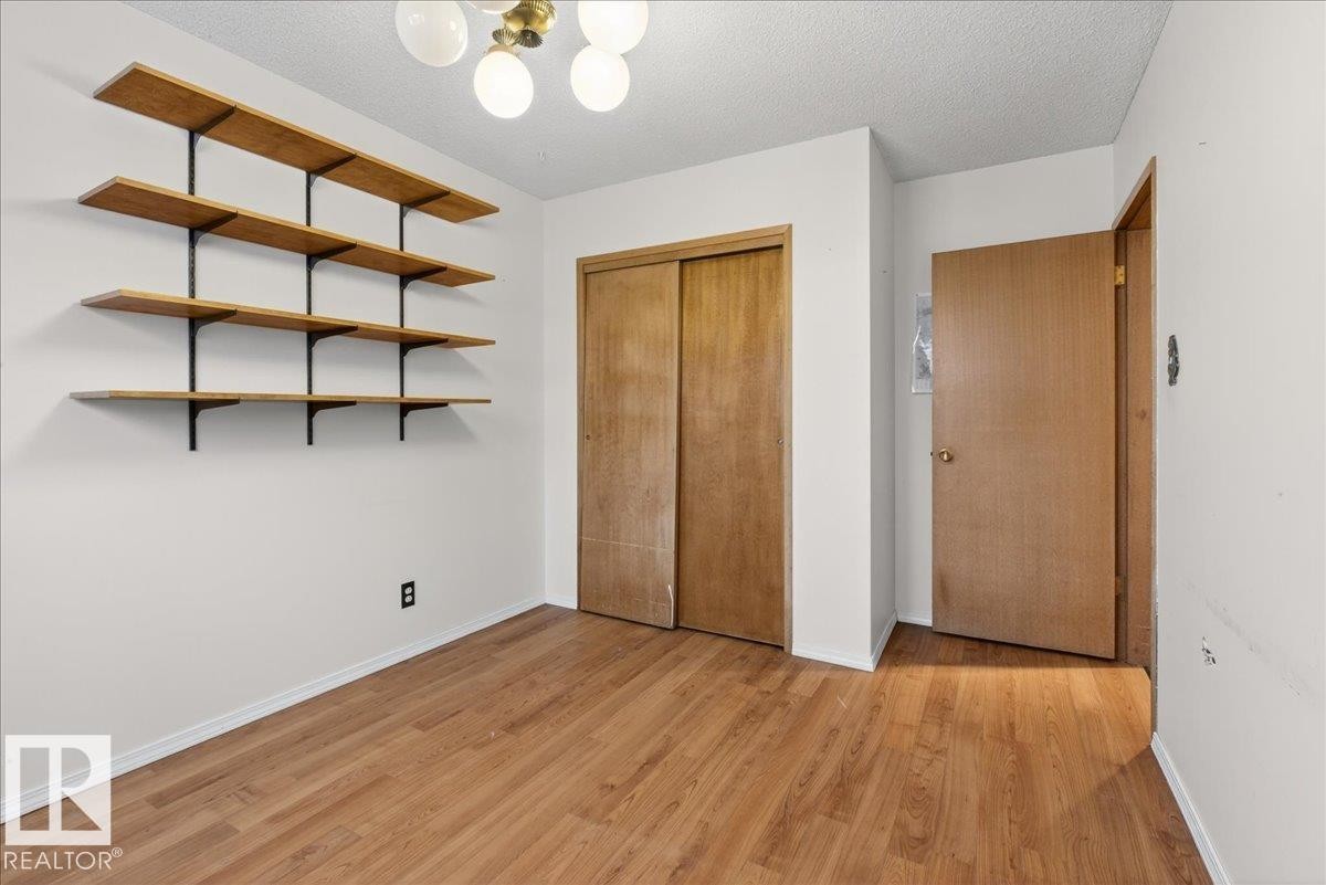 Unfurnished bedroom with a textured ceiling, light wood-style floors, a closet, and suspended lighting - Edmonton, AB - Indoor Photo Showing Other Room