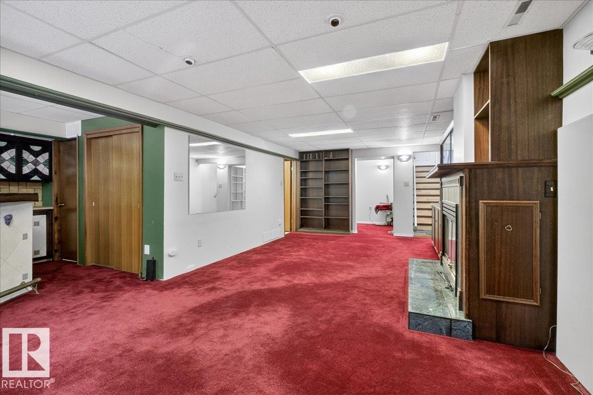 Finished basement featuring a drop ceiling, a fireplace, and carpet - Edmonton, AB - Indoor