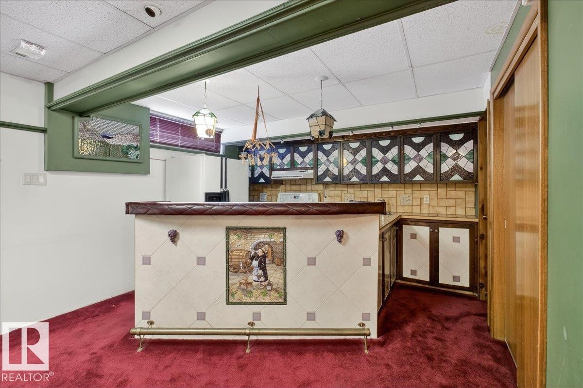 Indoor bar featuring a drop ceiling, dark carpet, white refrigerator with ice dispenser, and pendant lighting - Edmonton, AB - Photo Showing Other Room