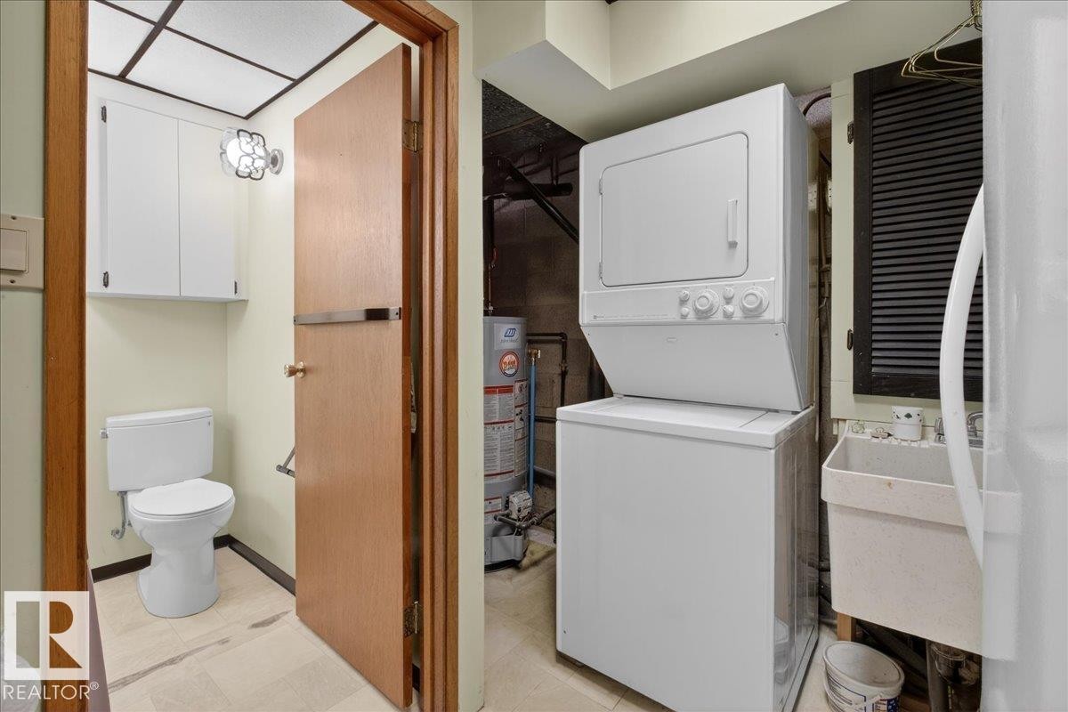 Laundry room with stacked washer and clothes dryer, gas water heater, and light flooring - Edmonton, AB - Indoor Photo Showing Laundry Room