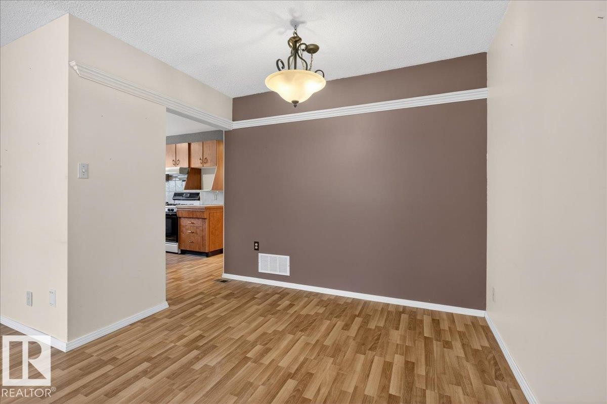 Unfurnished dining area featuring light wood-style floors and a textured ceiling - Edmonton, AB - Indoor Photo Showing Other Room