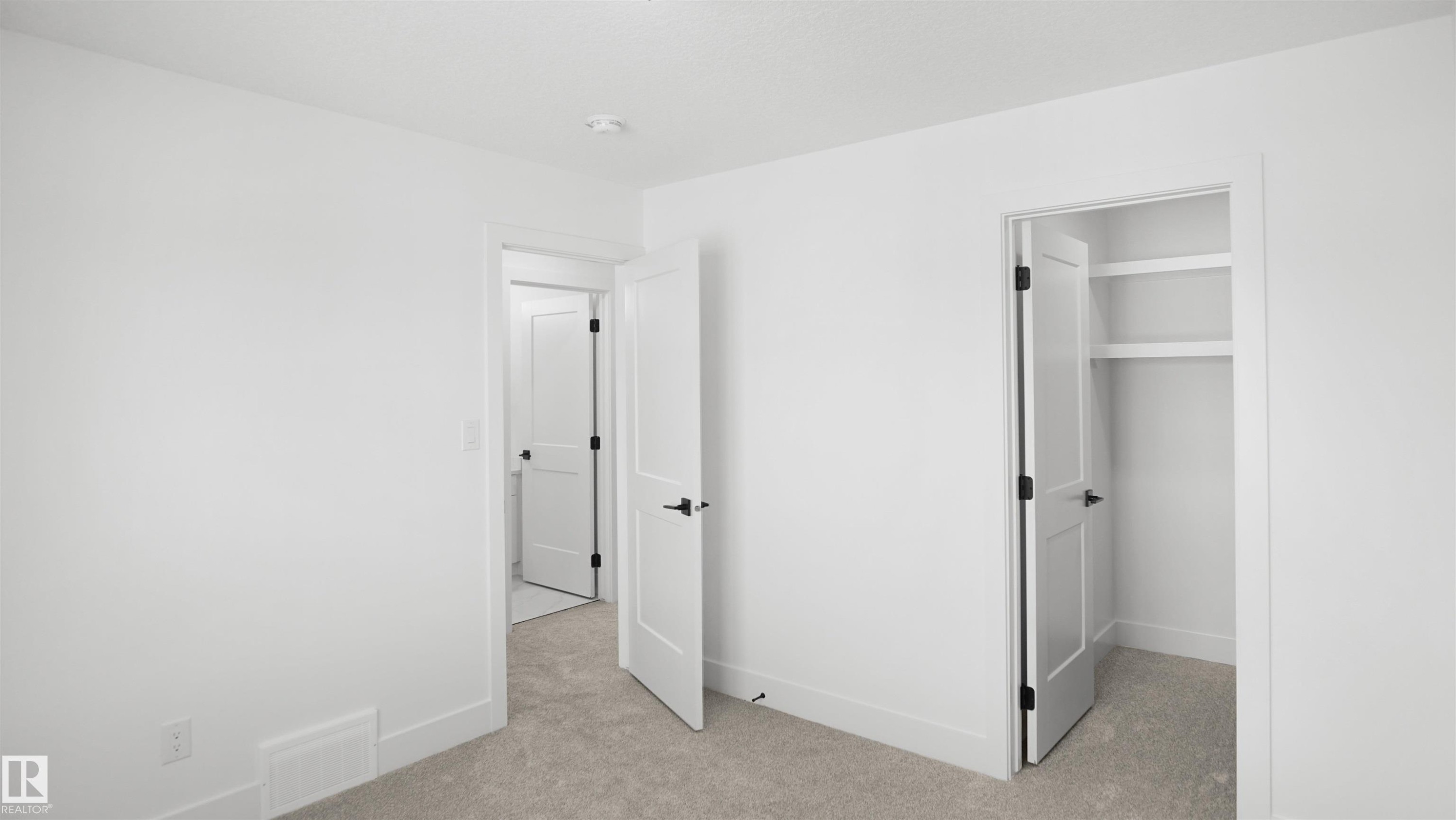 Unfurnished bedroom with light colored carpet and a walk in closet - 807 30 Avenue, Edmonton, AB - Indoor Photo Showing Other Room