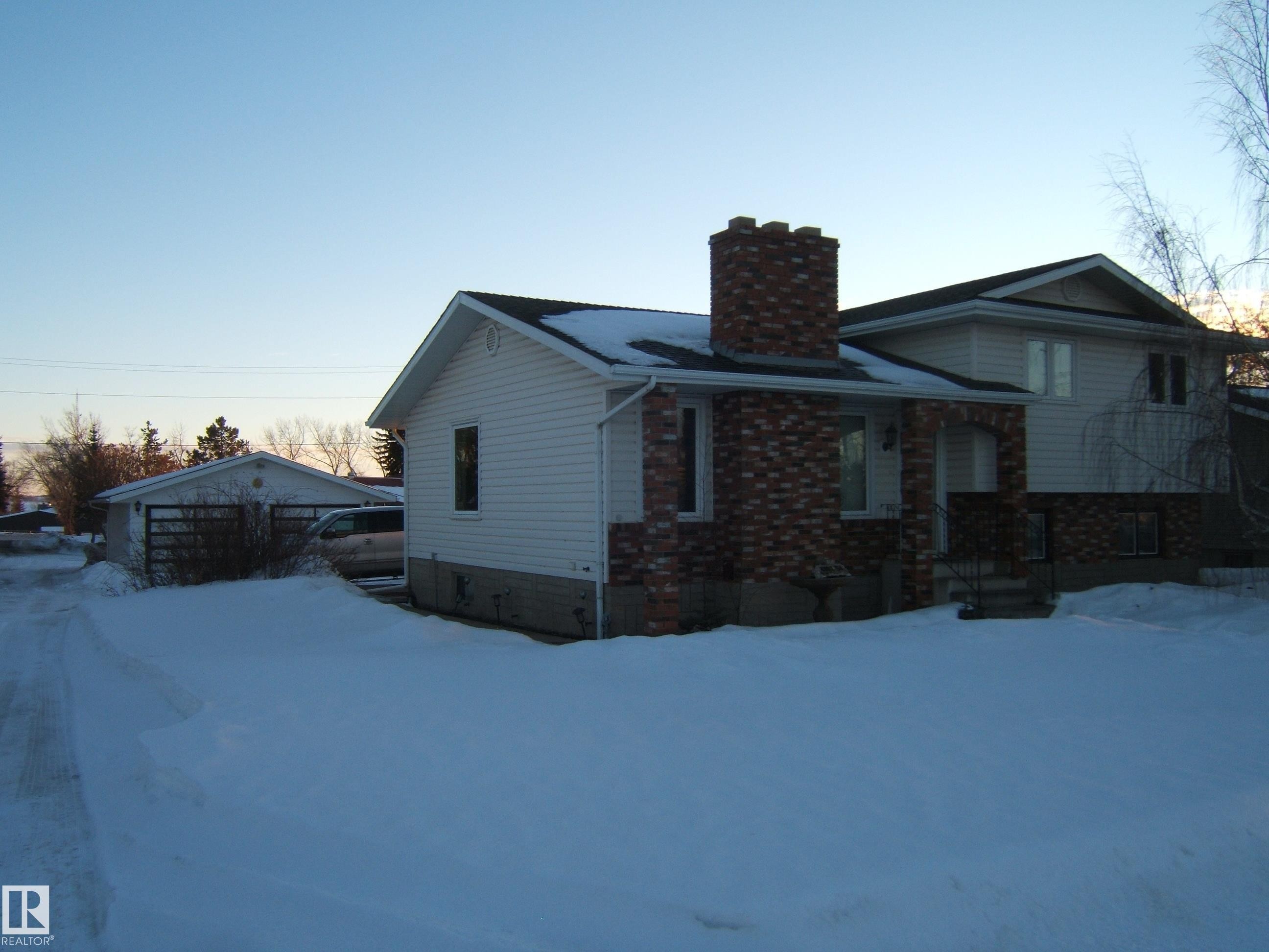 View of front of home with a chimney, brick siding, and an outdoor structure - 4807 54 Avenue, Two Hills, AB - Outdoor