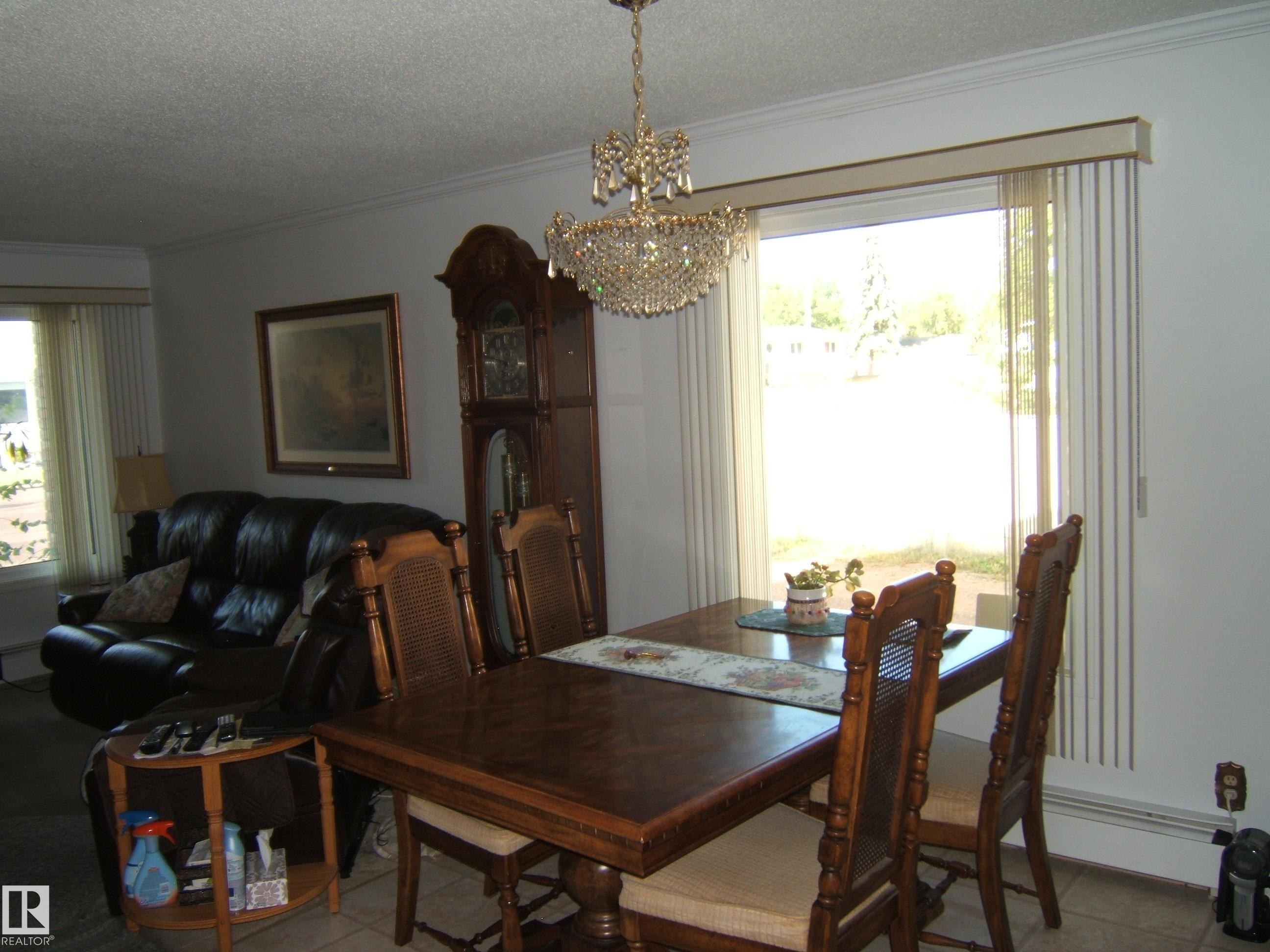 Dining space featuring ornamental molding, a textured ceiling, a chandelier, and tile patterned flooring - 4807 54 Avenue, Two Hills, AB - Indoor Photo Showing Dining Room