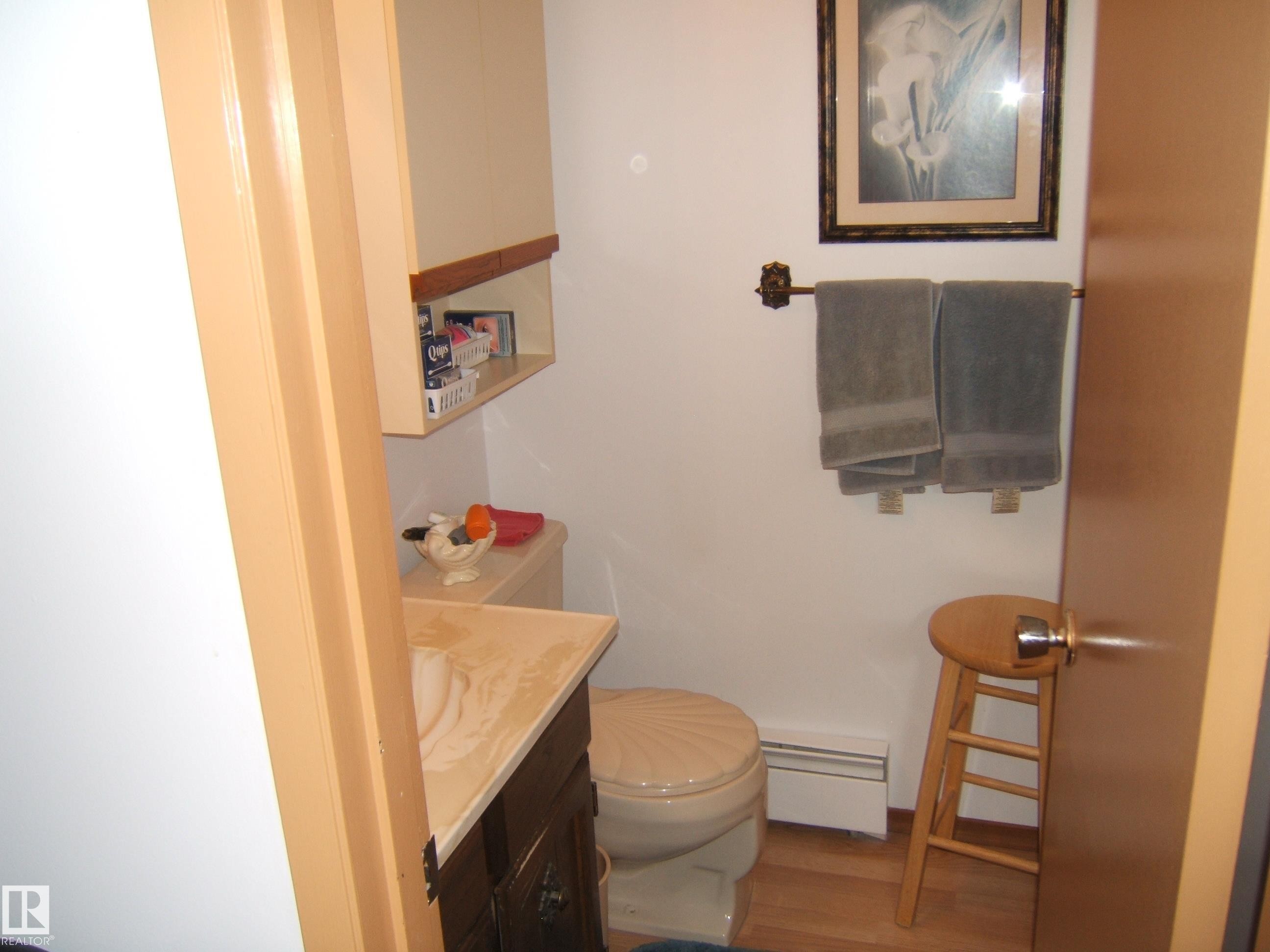 Bathroom featuring vanity, wood finished floors, and a baseboard heating unit - 4807 54 Avenue, Two Hills, AB - Indoor Photo Showing Bathroom