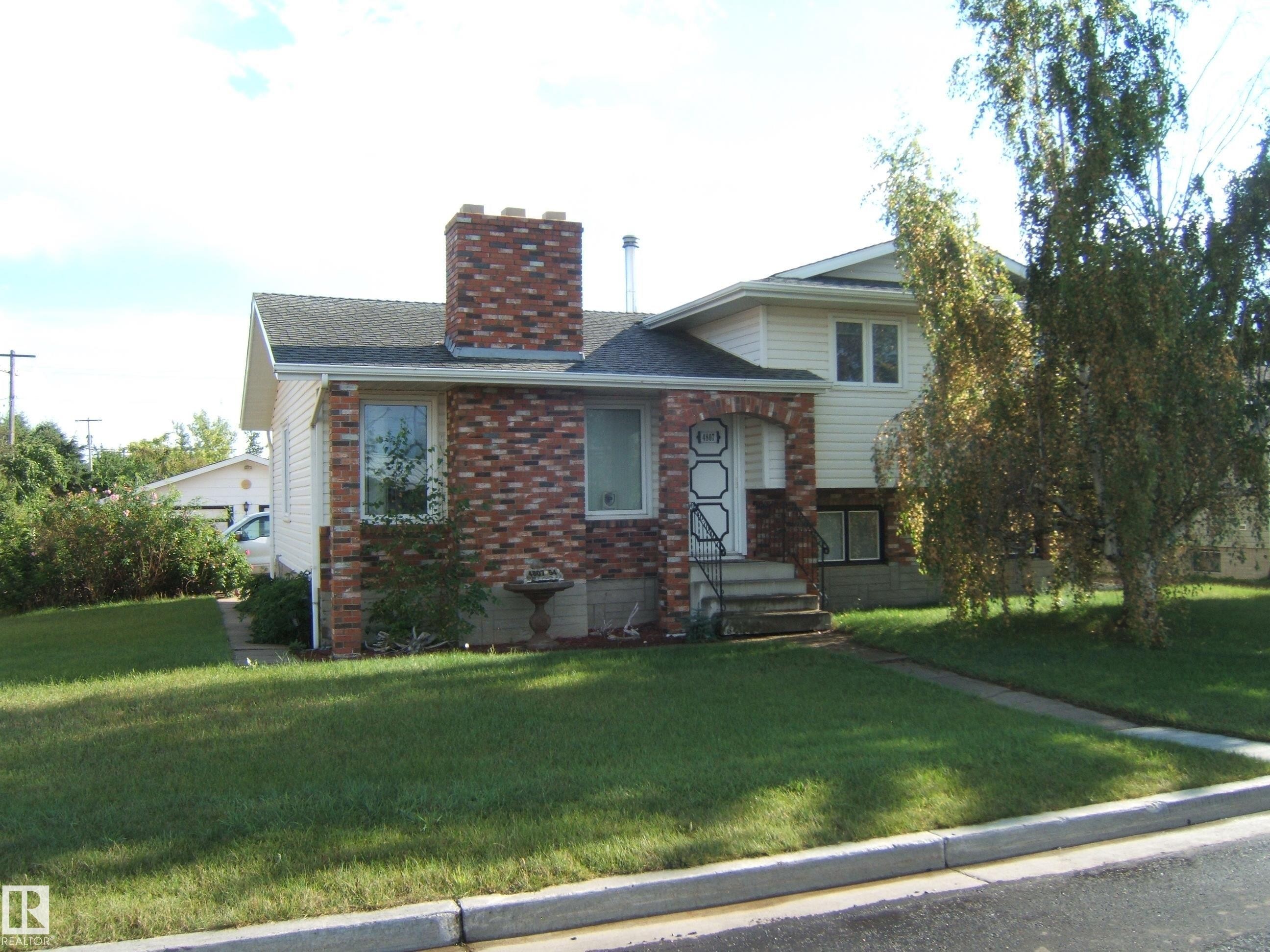 Tri-level home with a front lawn, a chimney, brick siding, and a shingled roof - 4807 54 Avenue, Two Hills, AB - Outdoor