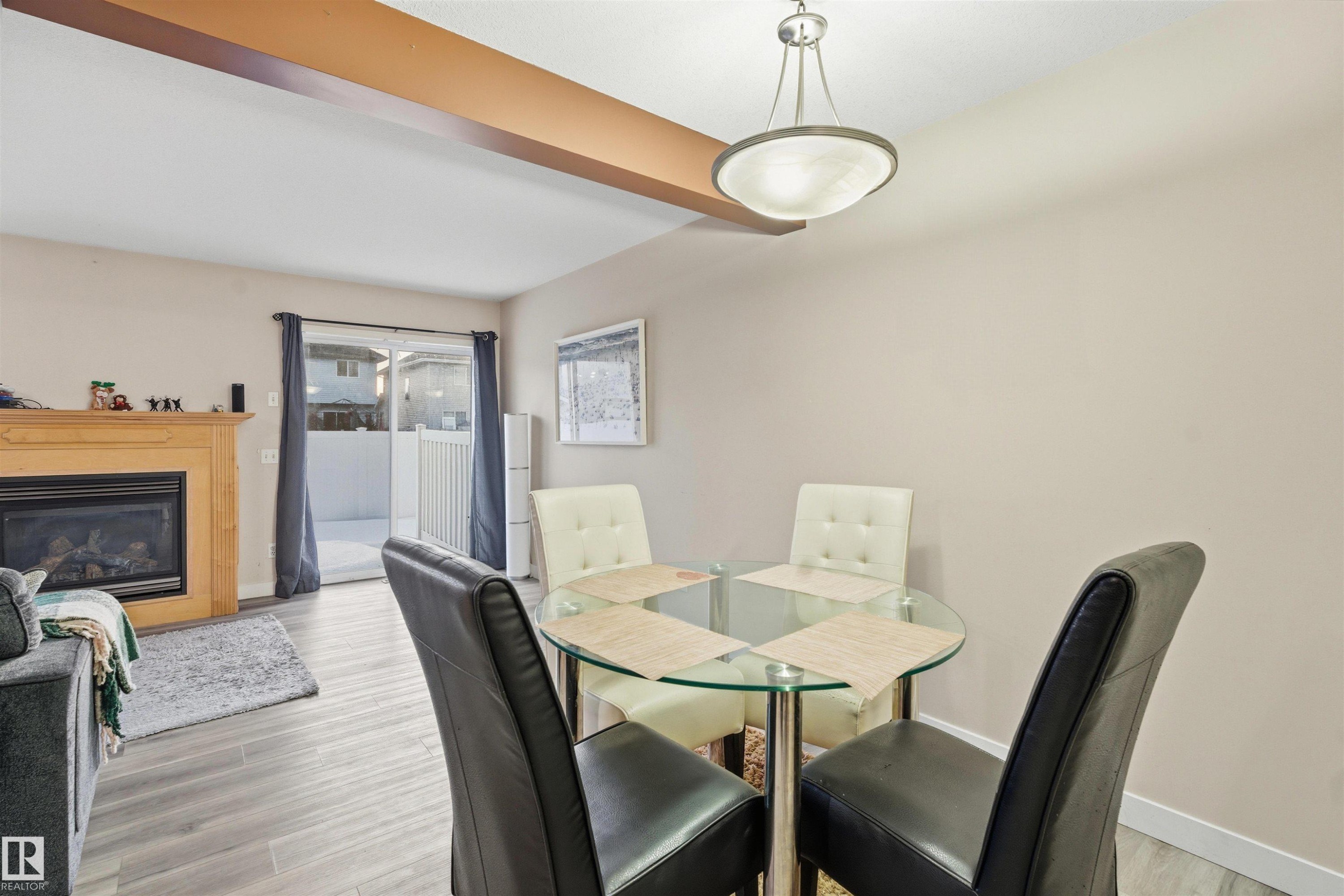 Dining area featuring a glass covered fireplace and light wood-style floors - 8 230 Edwards Drive, Edmonton, AB - Indoor Photo Showing Dining Room With Fireplace