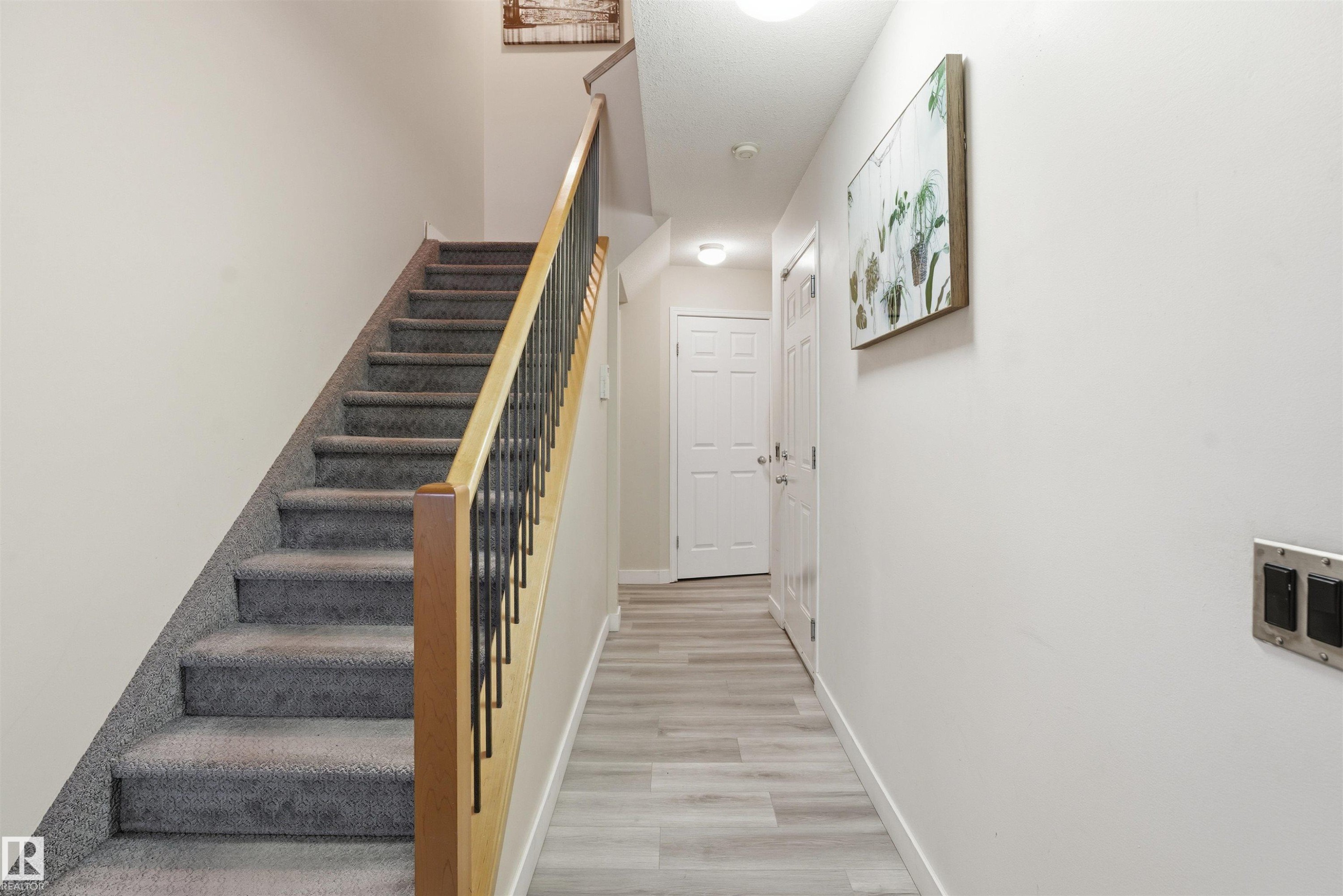 Stairway featuring baseboards and wood finished floors - 8 230 Edwards Drive, Edmonton, AB - Indoor Photo Showing Other Room
