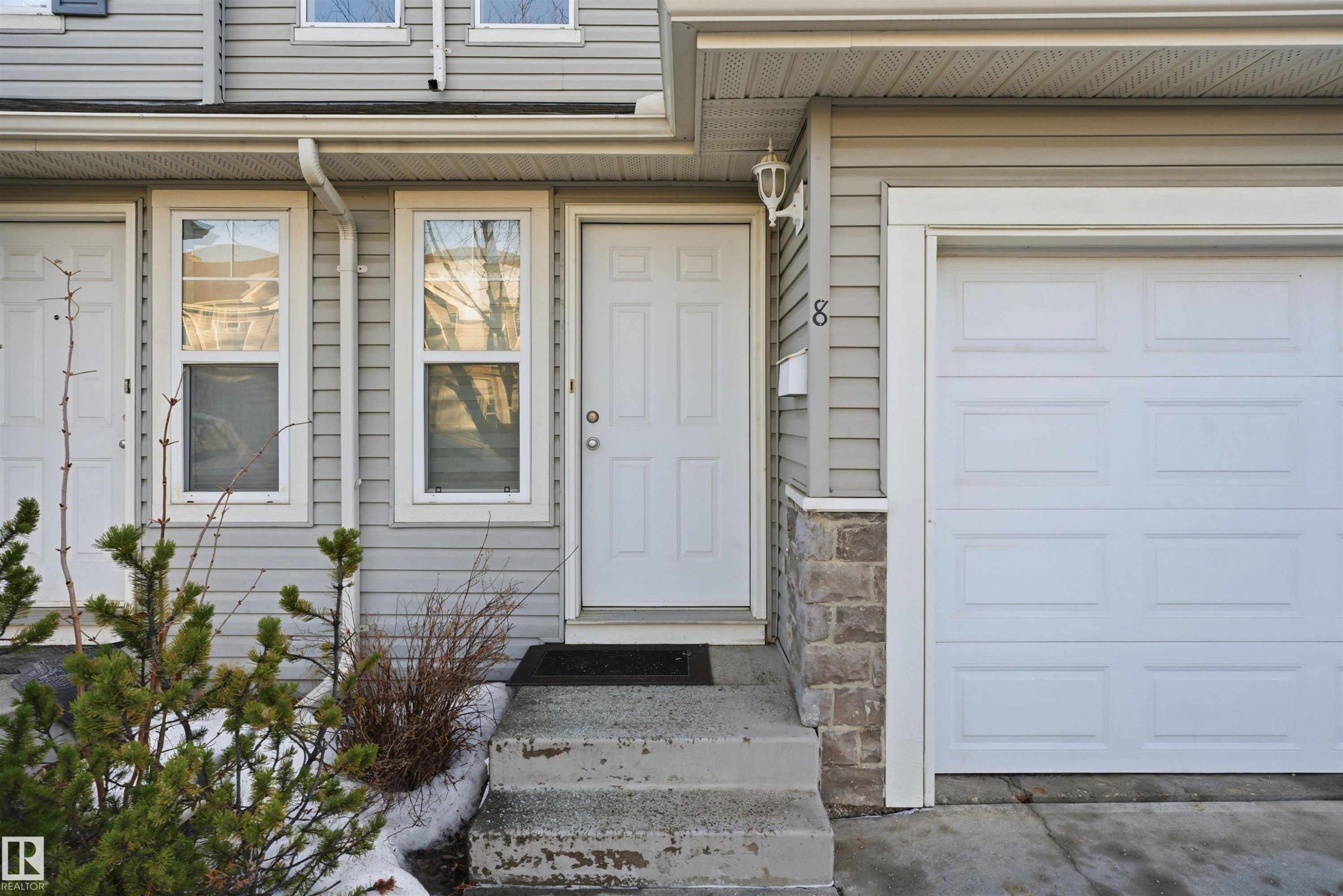 Doorway to property with a garage and stone siding - 8 230 Edwards Drive, Edmonton, AB - Outdoor With Exterior