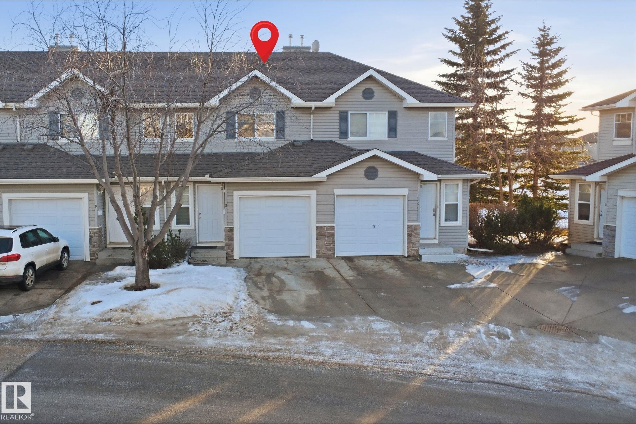 Traditional-style home with driveway, stone siding, a garage, and a shingled roof - 8 230 Edwards Drive, Edmonton, AB - Outdoor With Facade