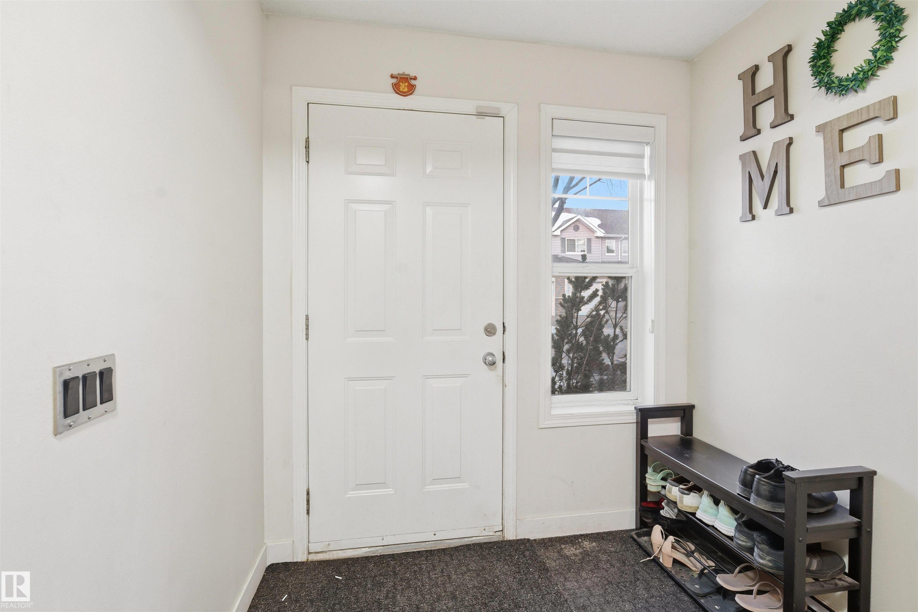 Foyer entrance with dark carpet and baseboards - 8 230 Edwards Drive, Edmonton, AB - Indoor Photo Showing Other Room