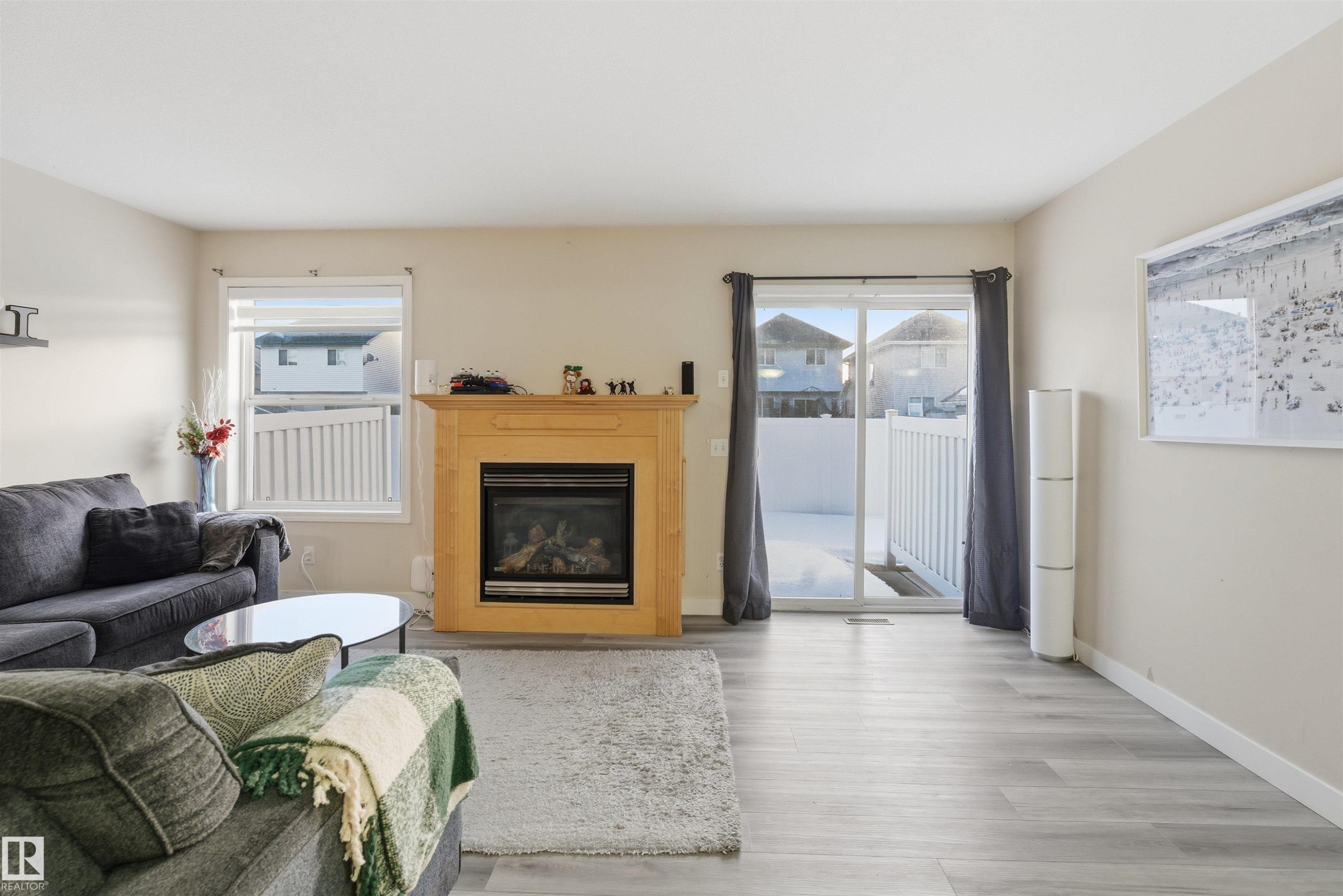 Living area featuring a glass covered fireplace and wood finished floors - 8 230 Edwards Drive, Edmonton, AB - Indoor Photo Showing Living Room With Fireplace