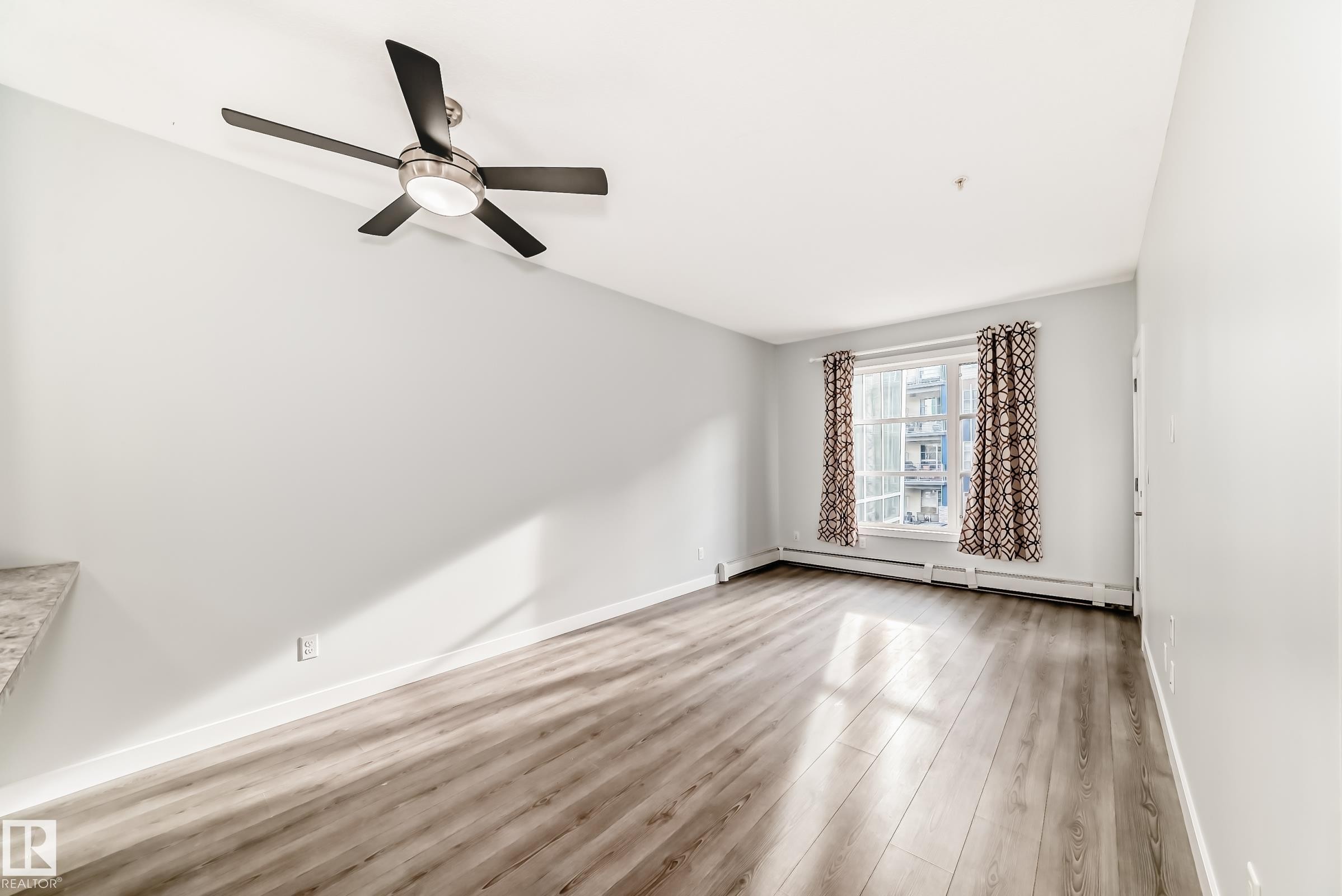 Unfurnished room featuring light wood finished floors, baseboard heating, and ceiling fan - 201 2588 Anderson Way, Edmonton, AB - Indoor Photo Showing Other Room