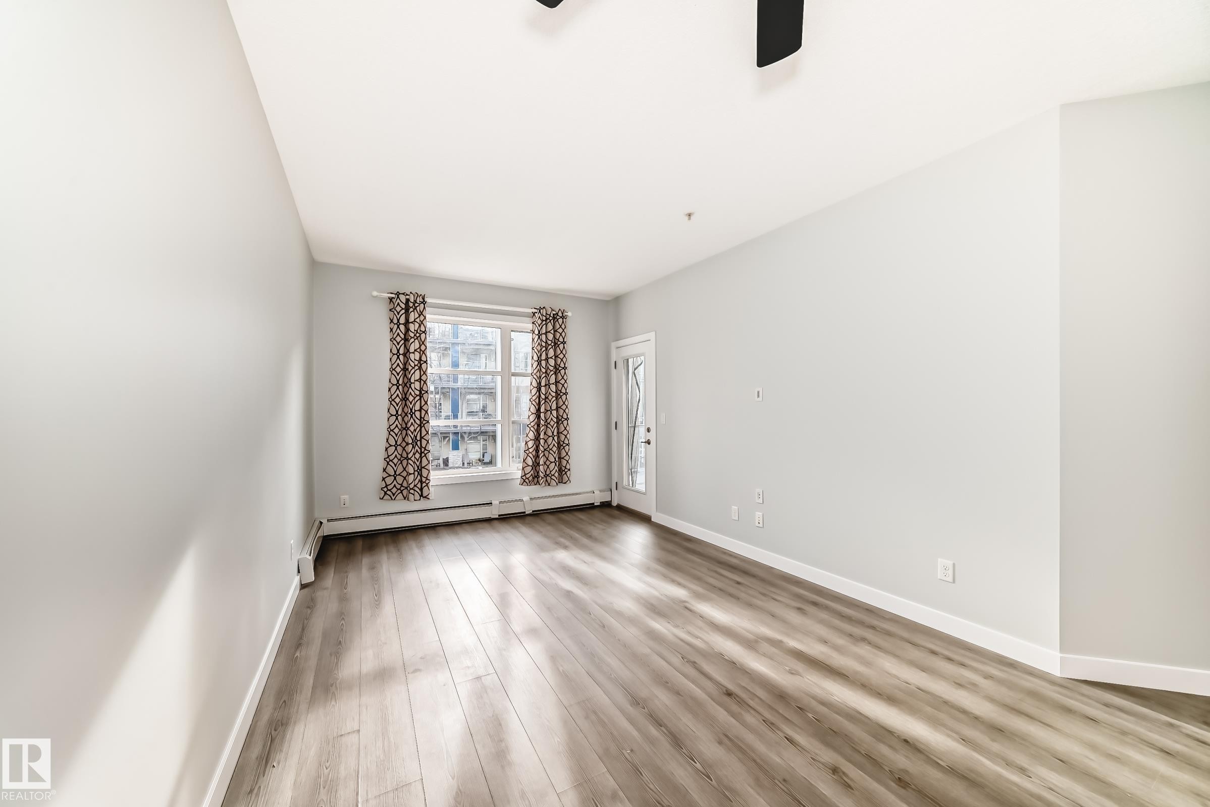 Spare room featuring light wood-type flooring, a ceiling fan, and baseboard heating - 201 2588 Anderson Way, Edmonton, AB - Indoor Photo Showing Other Room
