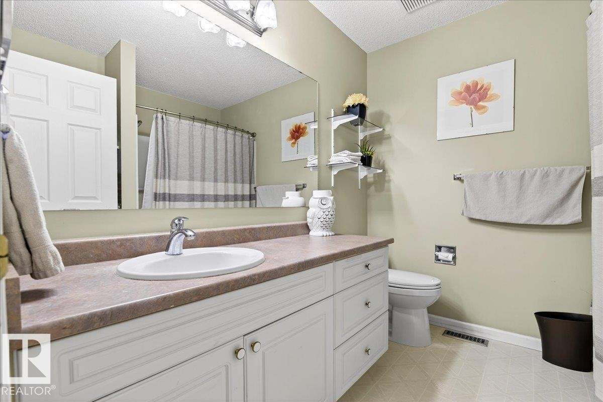 Bathroom with vanity, a shower with curtain, a textured ceiling, and light flooring - 13217 155 Avenue Nw, Edmonton, AB - Indoor Photo Showing Bathroom