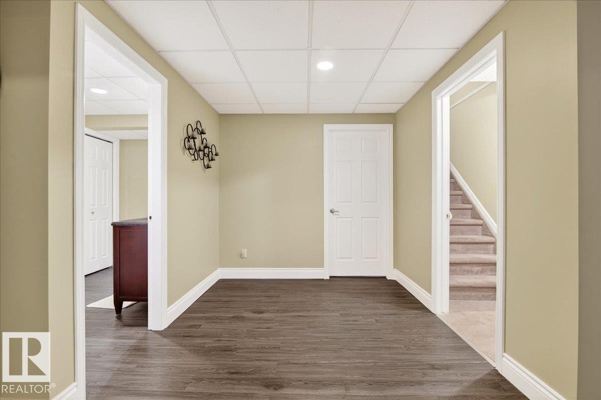 Empty room featuring dark wood-style floors, a paneled ceiling, and recessed lighting - 13217 155 Avenue Nw, Edmonton, AB - Indoor Photo Showing Other Room