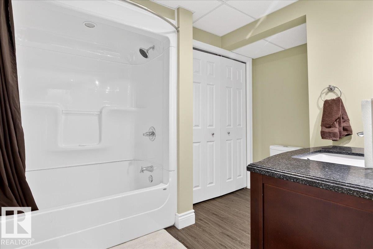 Full bath with vanity, shower / tub combo with curtain, a closet, dark wood-type flooring, and a drop ceiling - 13217 155 Avenue Nw, Edmonton, AB - Indoor Photo Showing Bathroom
