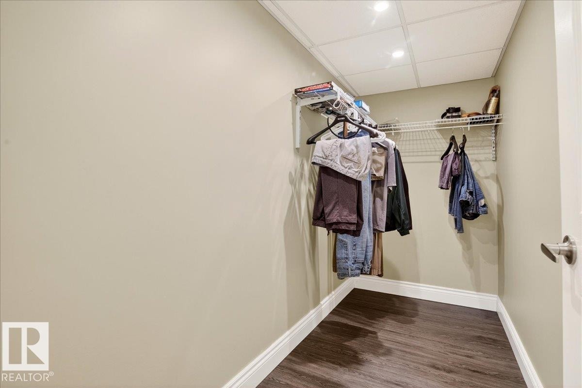 Walk in closet featuring a drop ceiling and dark wood-type flooring - 13217 155 Avenue Nw, Edmonton, AB - Indoor With Storage