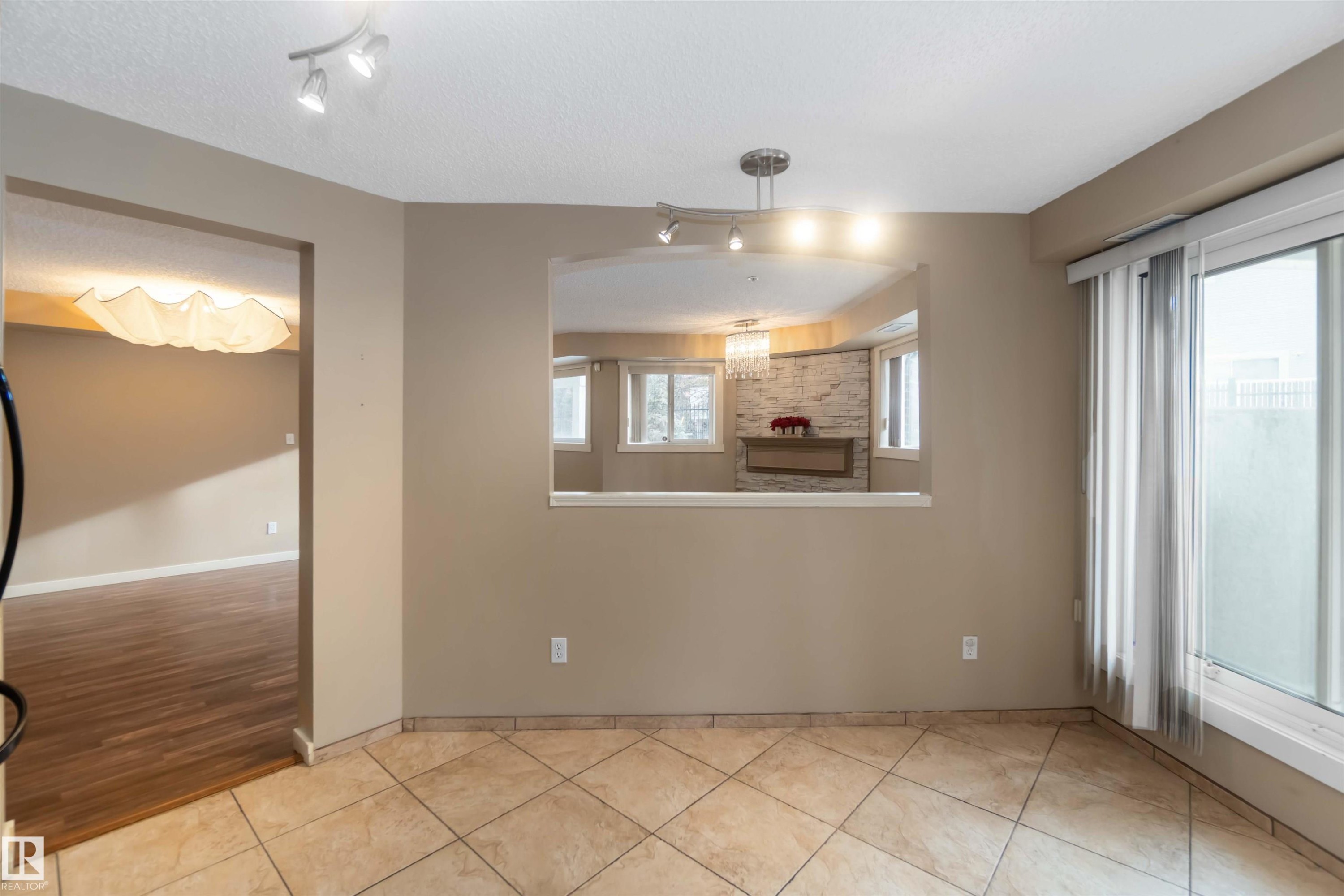 Unfurnished dining area featuring rail lighting, light tile patterned floors, and a textured ceiling - 113 10311 111 Street, Edmonton, AB - Indoor Photo Showing Other Room