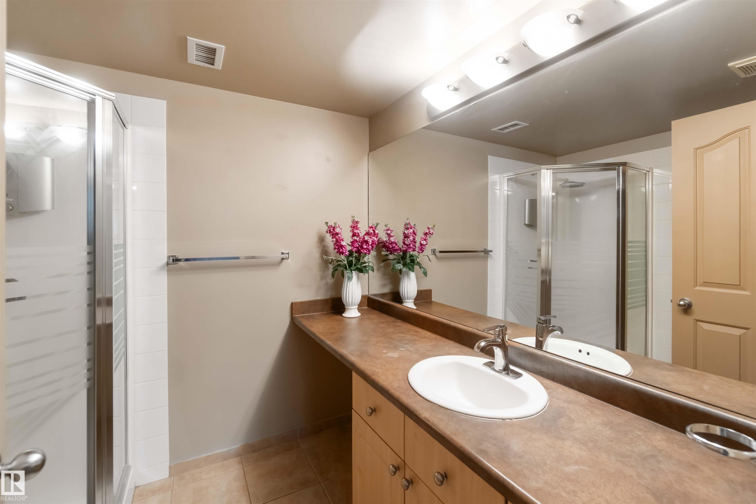 Full bathroom with a shower stall, vanity, and light tile patterned floors - 113 10311 111 Street, Edmonton, AB - Indoor Photo Showing Bathroom