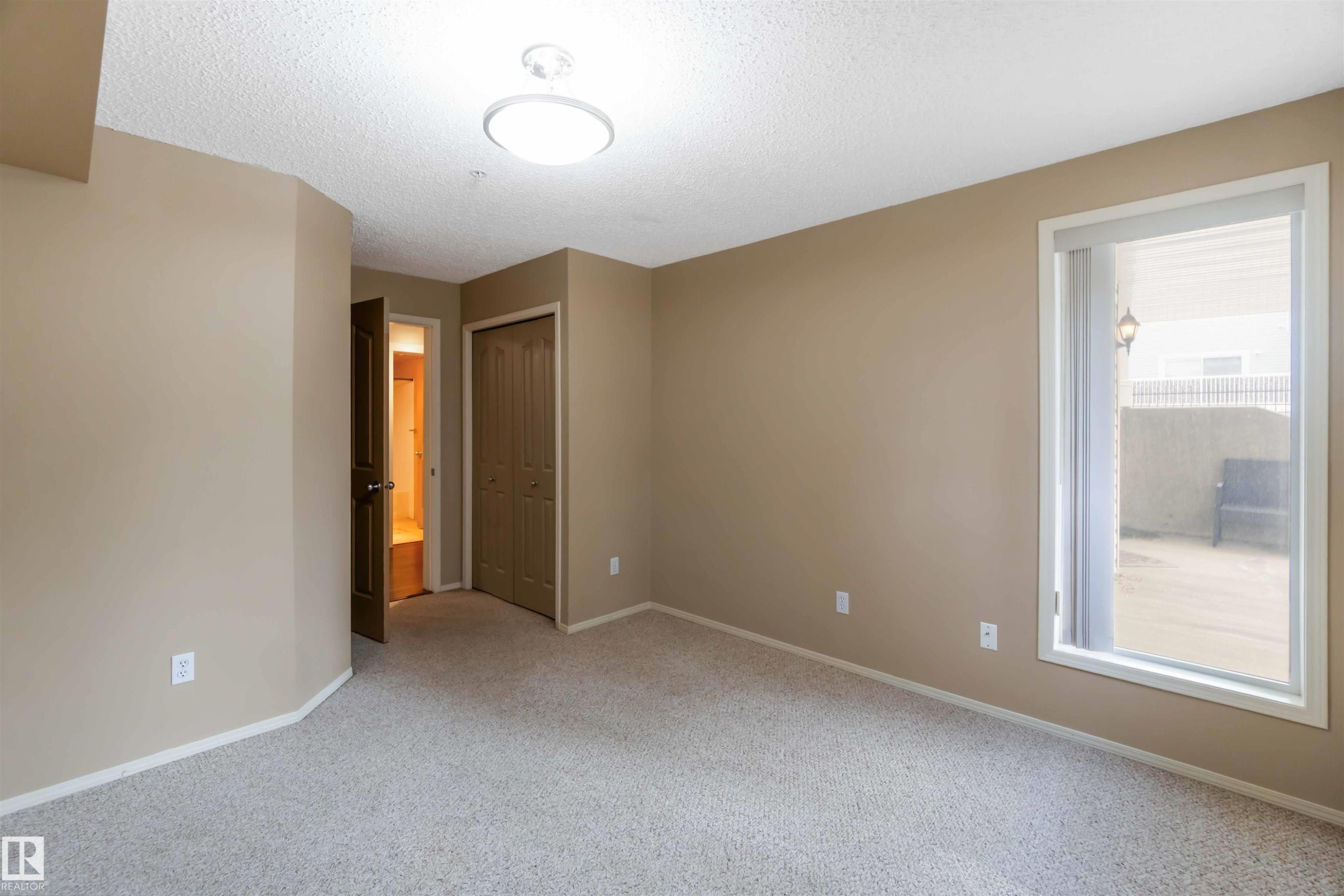Unfurnished room with light carpet and a textured ceiling - 113 10311 111 Street, Edmonton, AB - Indoor Photo Showing Other Room