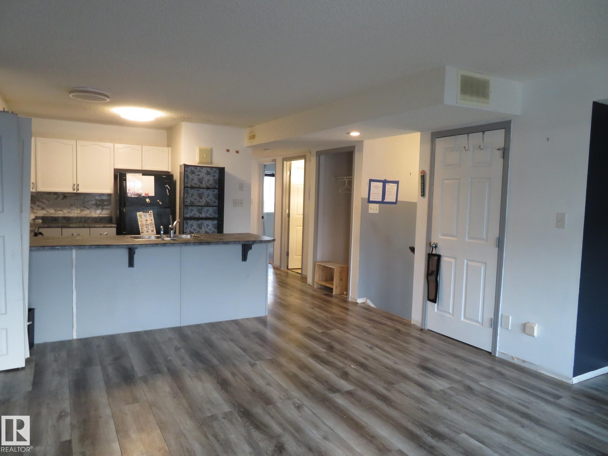 Kitchen with dark countertops, white cabinetry, freestanding refrigerator, a kitchen bar, and recessed lighting - 2945 26 Street, Edmonton, AB - Indoor Photo Showing Kitchen