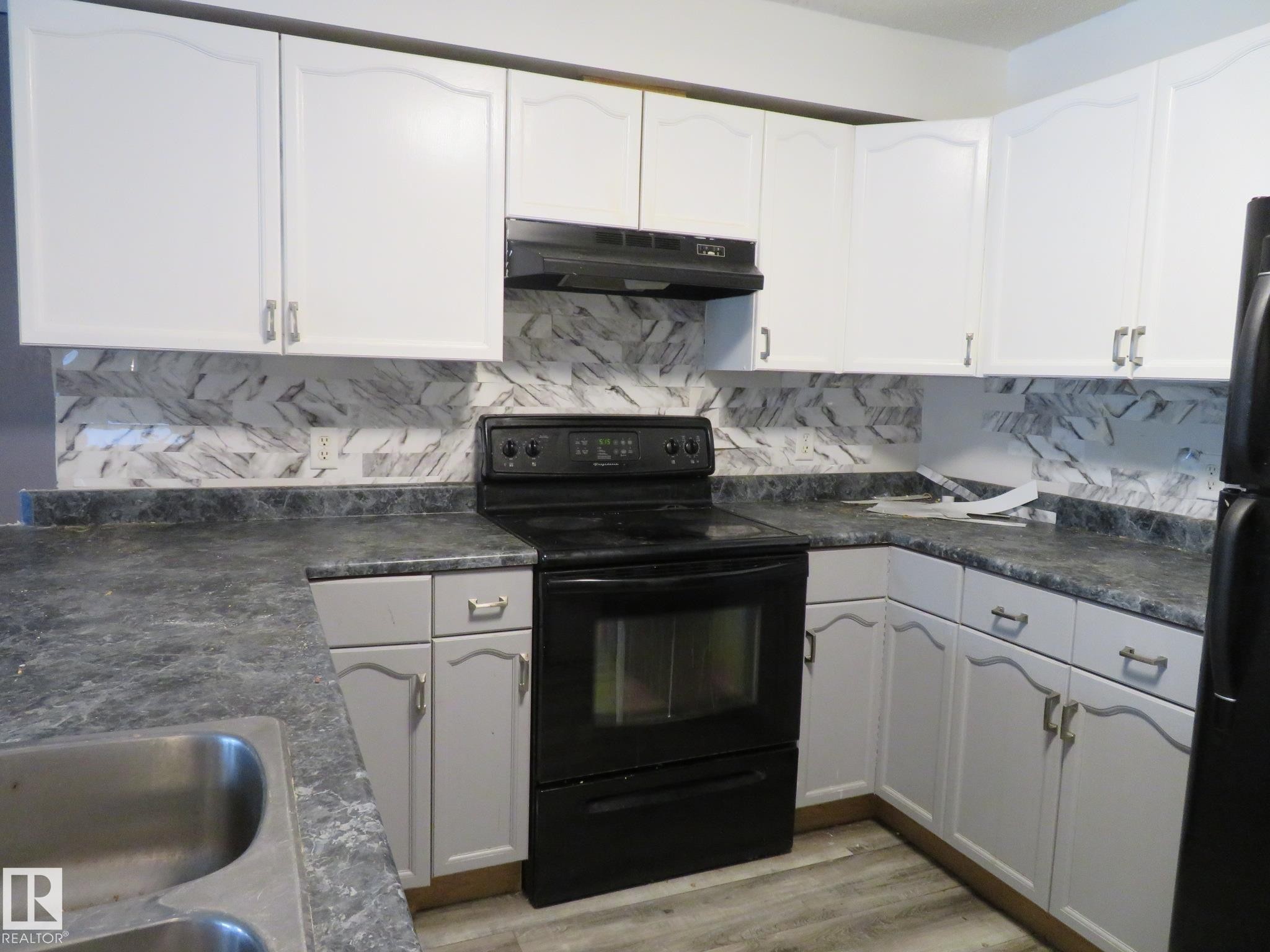 Kitchen with dark countertops, black appliances, tasteful backsplash, light wood finished floors, and white cabinetry - 2945 26 Street, Edmonton, AB - Indoor Photo Showing Kitchen