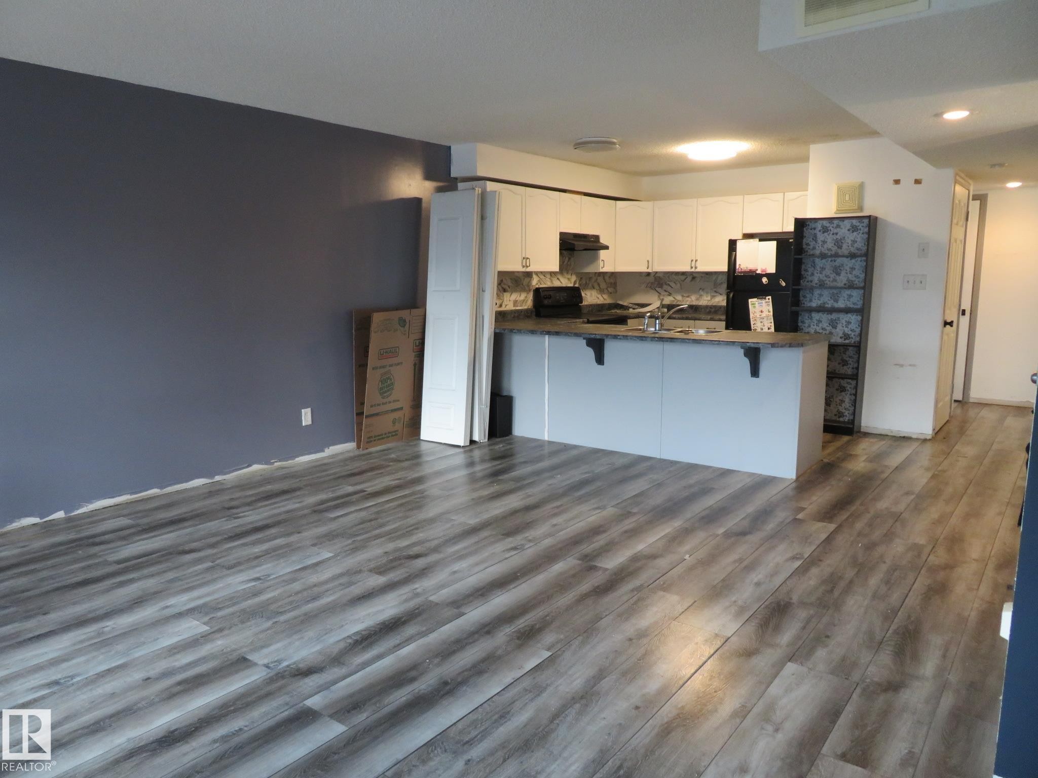 Kitchen featuring dark countertops, dark wood finished floors, white cabinets, and black appliances - 2945 26 Street, Edmonton, AB - Indoor Photo Showing Kitchen