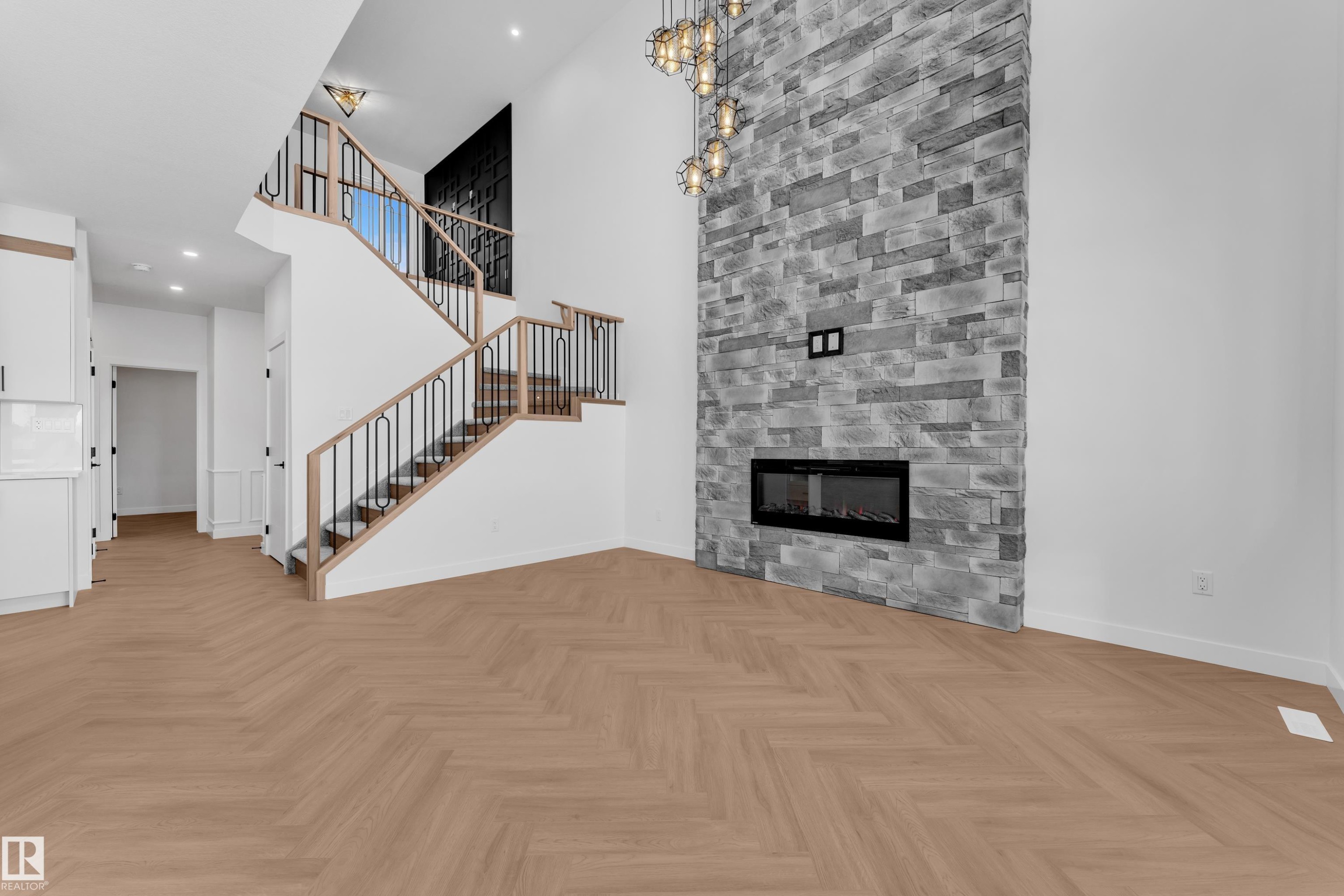 Unfurnished living room featuring parquet flooring, a high ceiling, recessed lighting, and a stone fireplace - 38 Grayson Green, Stony Plain, AB - Indoor Photo Showing Living Room With Fireplace