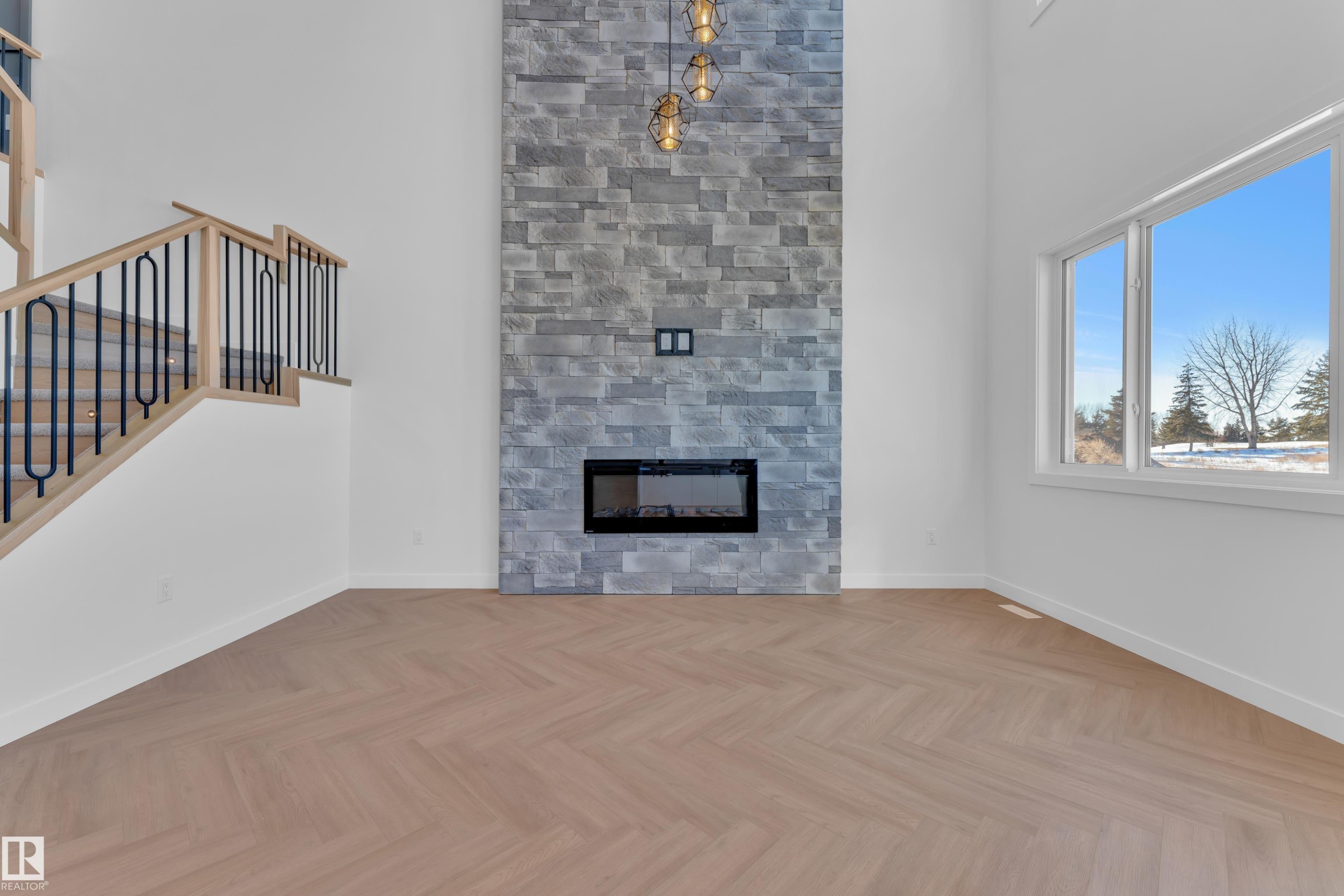 Unfurnished living room featuring a high ceiling, parquet floors, and a glass covered fireplace - 38 Grayson Green, Stony Plain, AB - Indoor Photo Showing Living Room With Fireplace