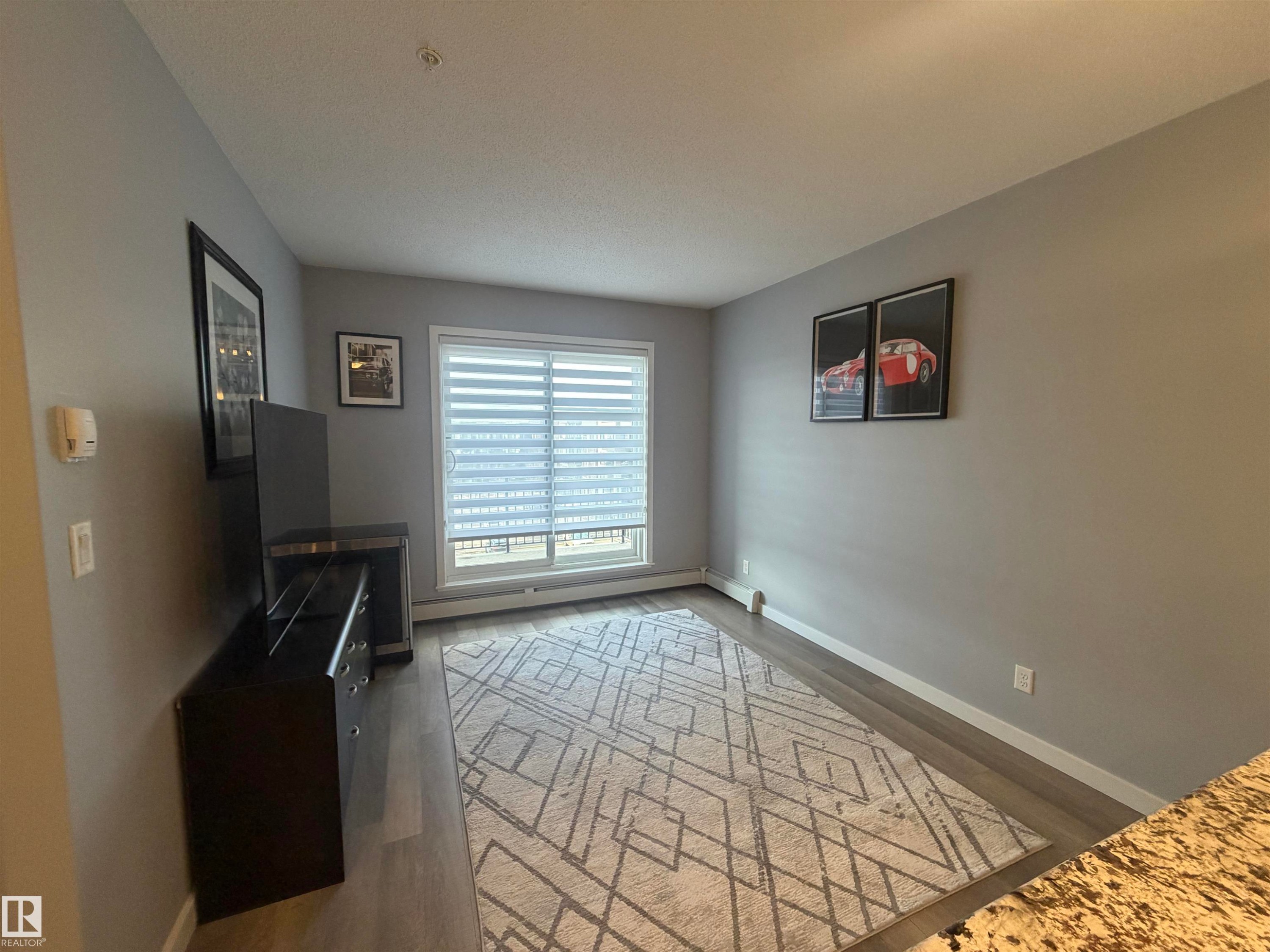 Unfurnished living room featuring a baseboard heating unit and light wood-style floors - 417 1004 Rosenthal Boulevard, Edmonton, AB - Indoor Photo Showing Other Room