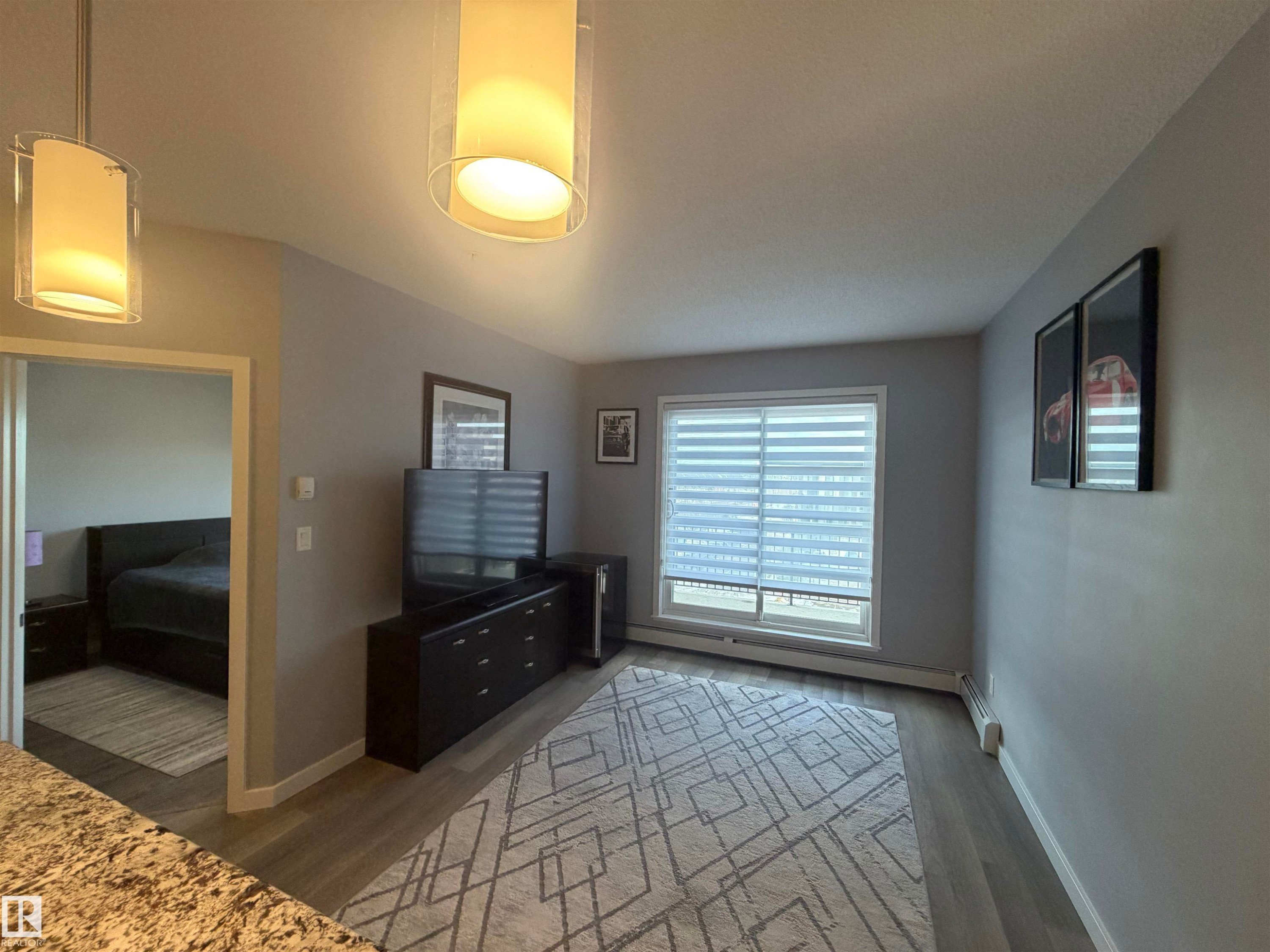 Bedroom with wood finished floors and a baseboard radiator - 417 1004 Rosenthal Boulevard, Edmonton, AB - Indoor Photo Showing Other Room