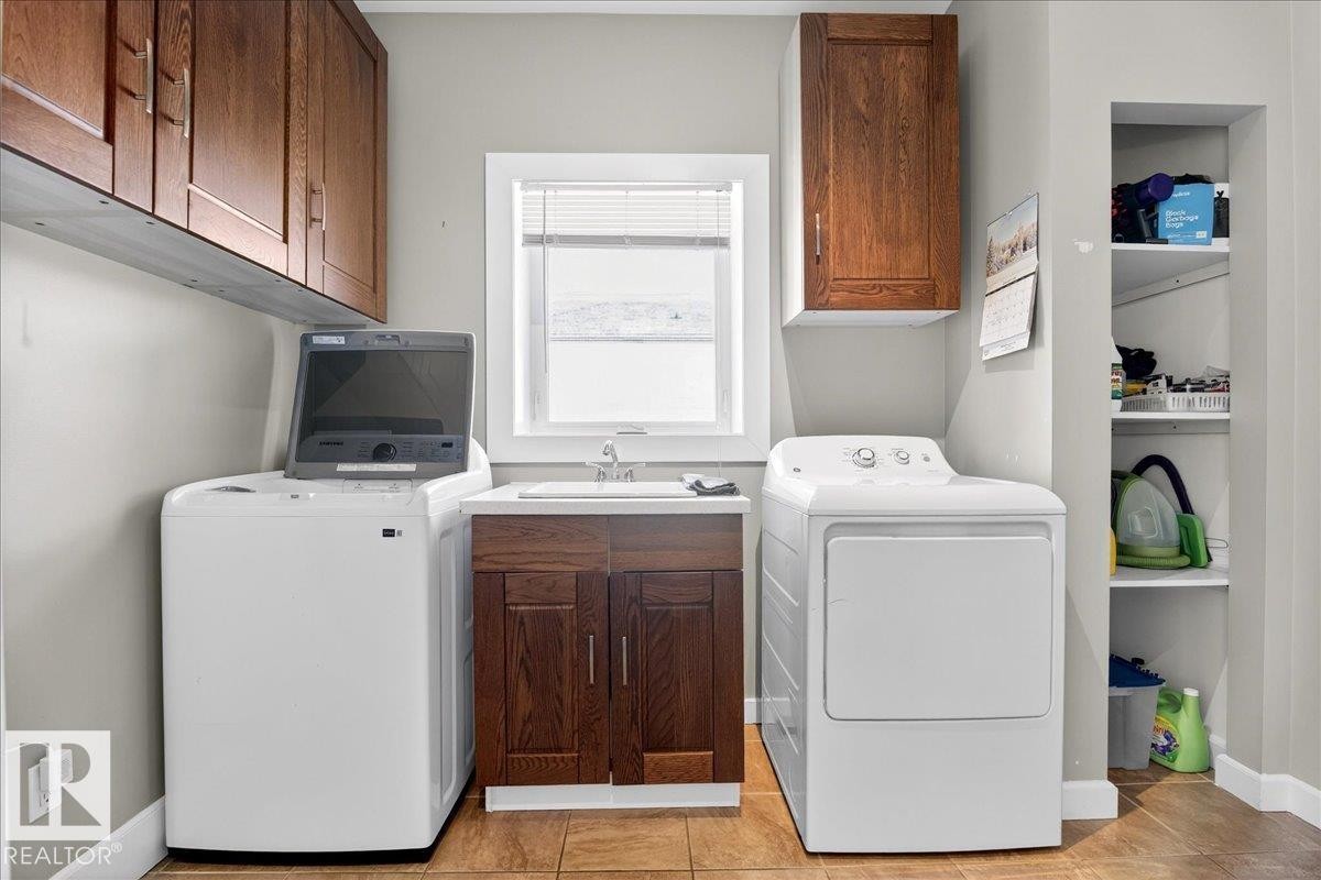 Laundry area with cabinet space, washing machine and dryer, and light tile patterned floors - 5019 48 Avenue, Chipman, AB - Indoor Photo Showing Laundry Room