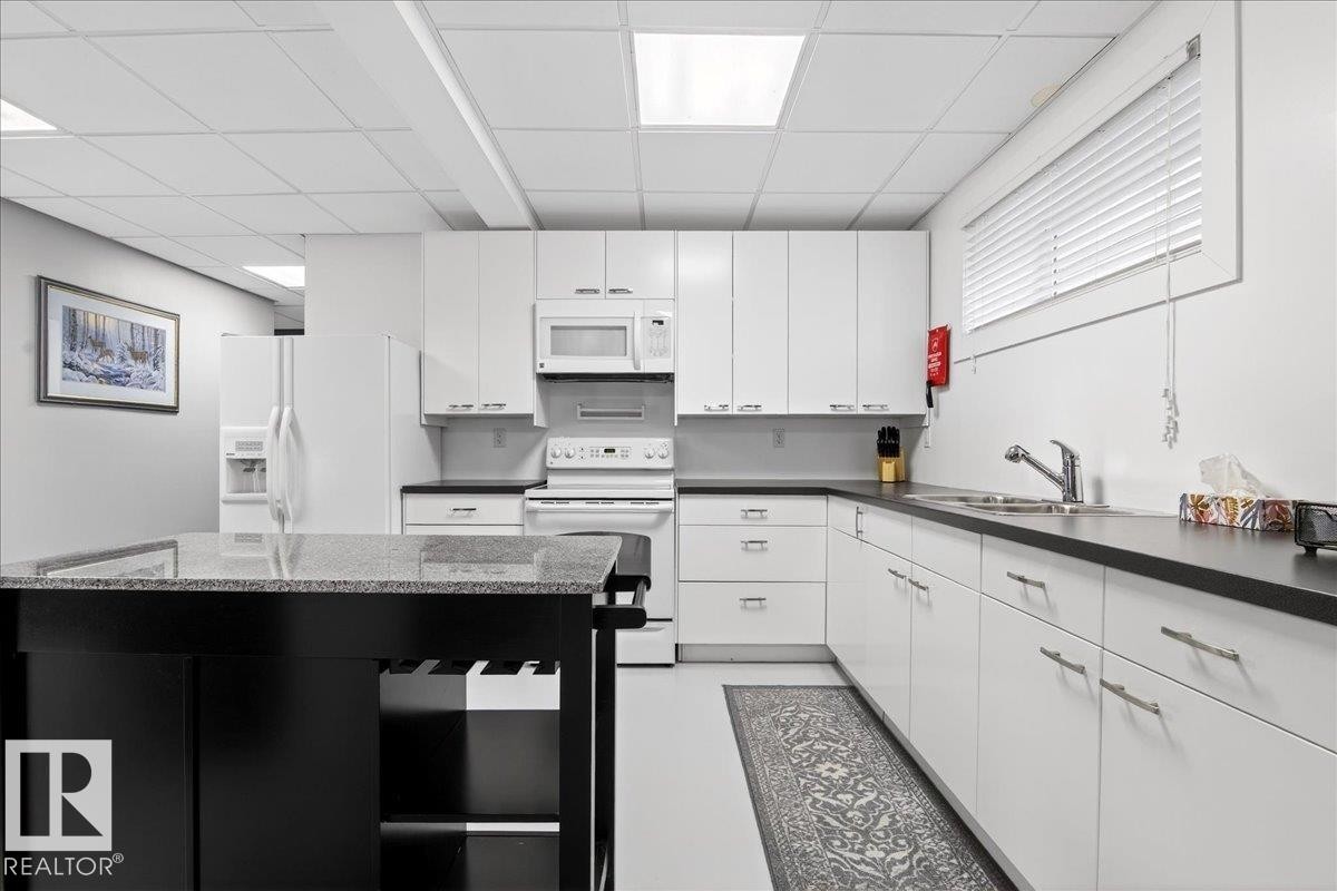 Kitchen with white appliances, a drop ceiling, and white cabinets - 5019 48 Avenue, Chipman, AB - Indoor Photo Showing Kitchen With Double Sink